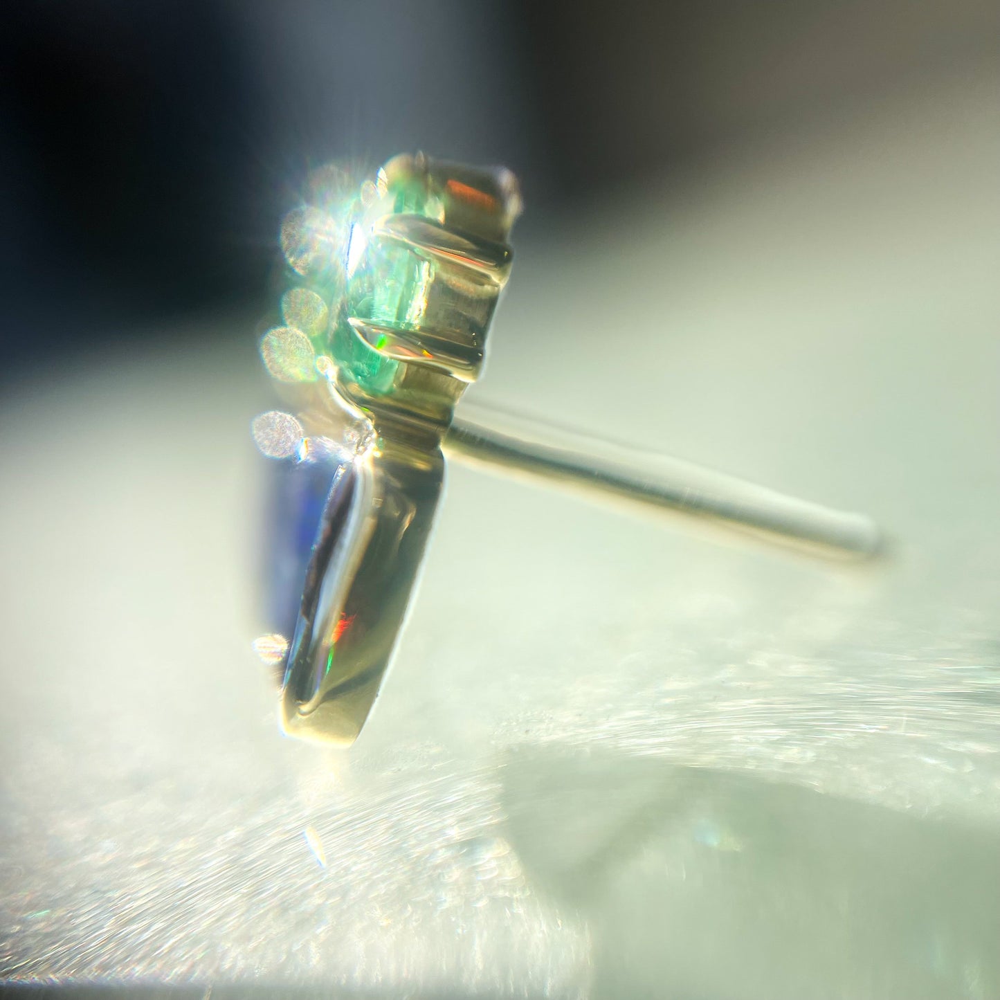 Magnified shot of Australian Opal Earrings by NIXIN Jewelry showing their profile. Displays the bezel setting and claw prongs.