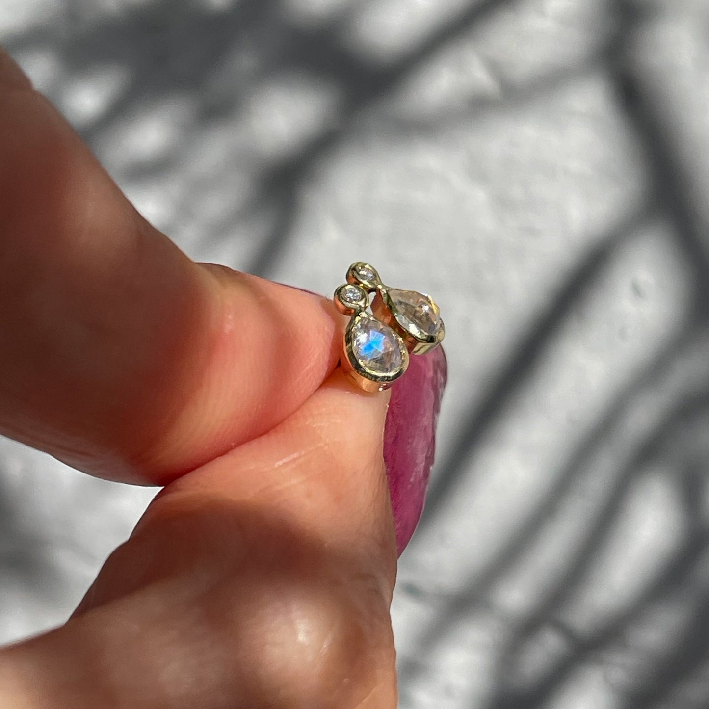 Moonstone Earrings by NIXIN Jewelry held in front of a grey backdrop and shot in profile. June birthstone jewelry.