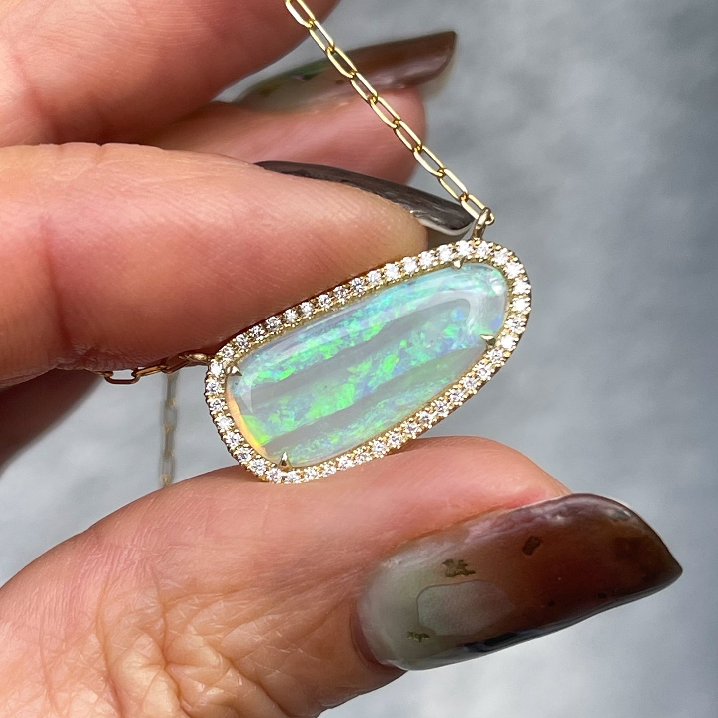An Australian Opal Necklace by NIXIN Jewelry with a natural opal set in claw prongs. A gold opal necklace.