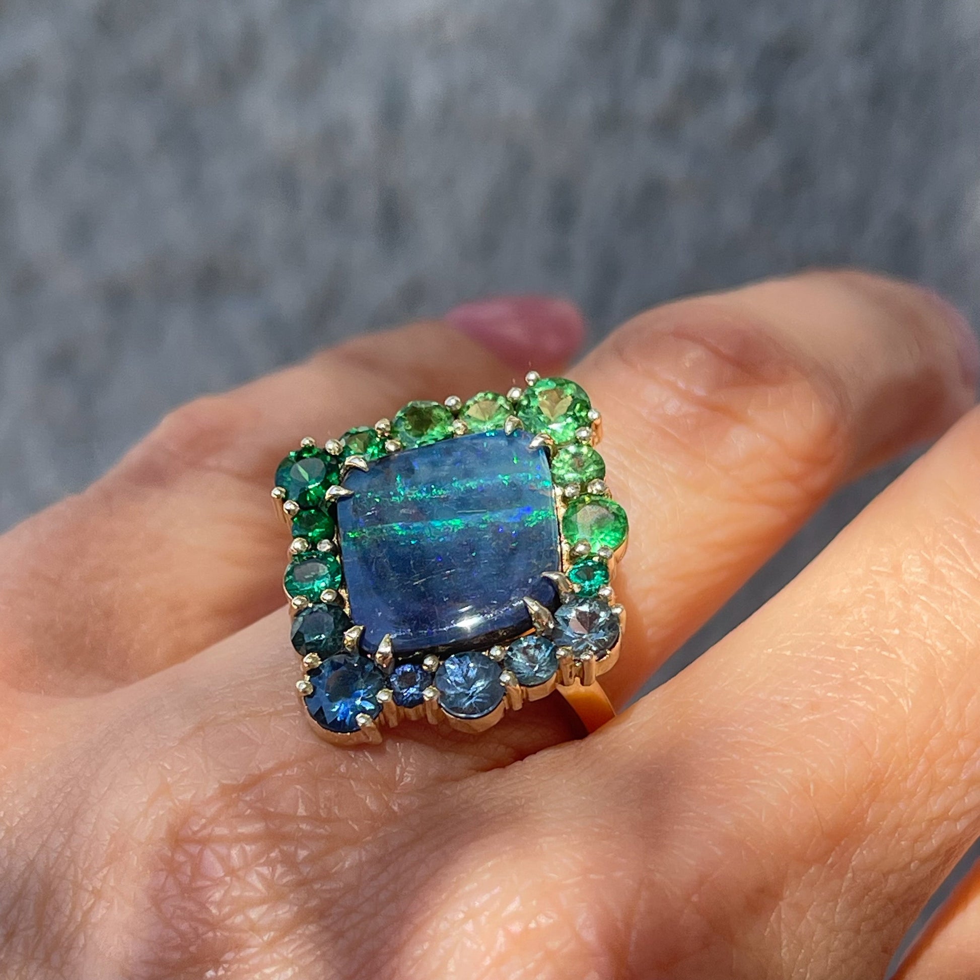 An angled view of an Australian Opal Ring by NIXIN Jewelry worn on the hand. Feature a blue opal.