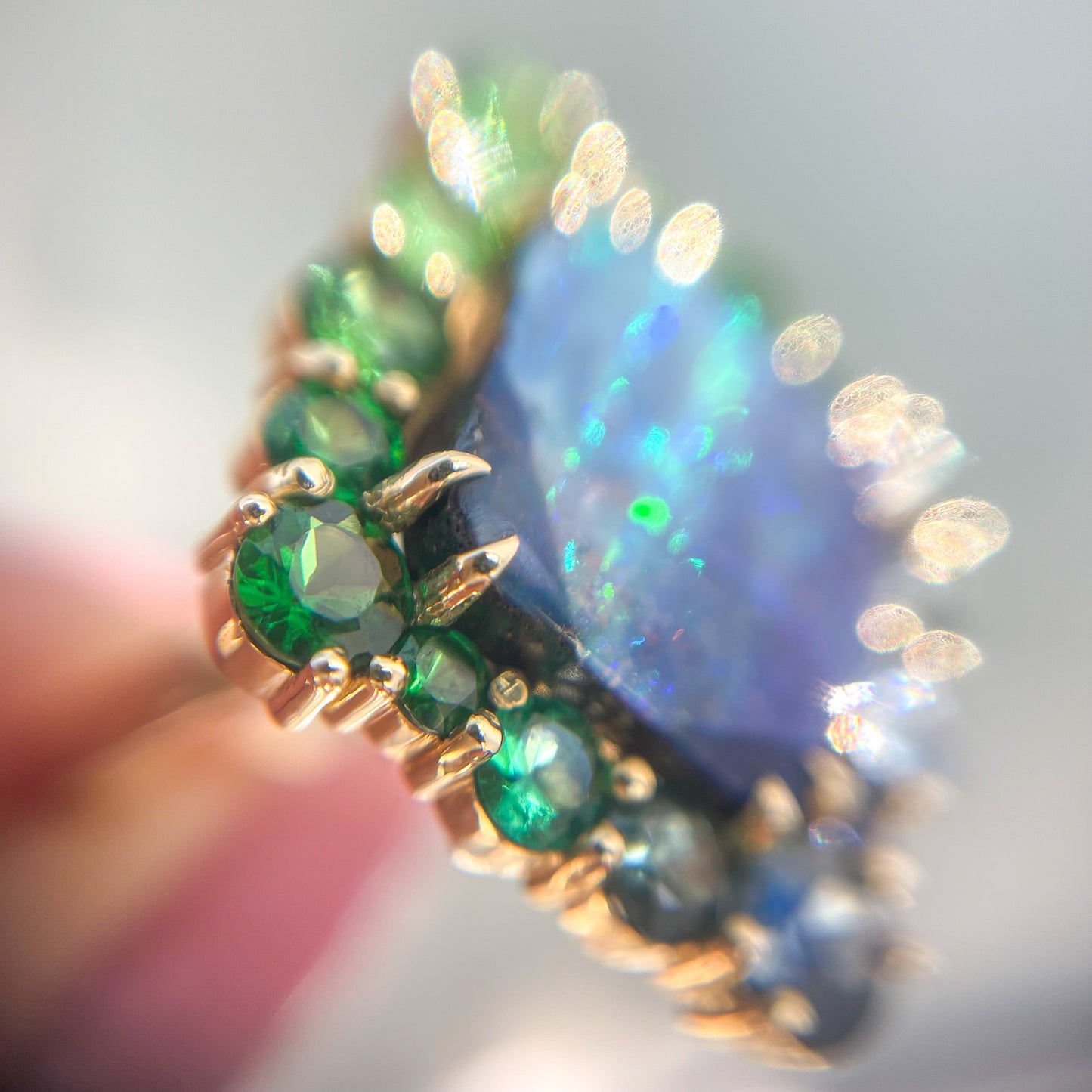 Magnified shot of an Australian Opal Ring by NIXIN Jewelry. Showing the garnet and emerald halo around the Boulder Opal.