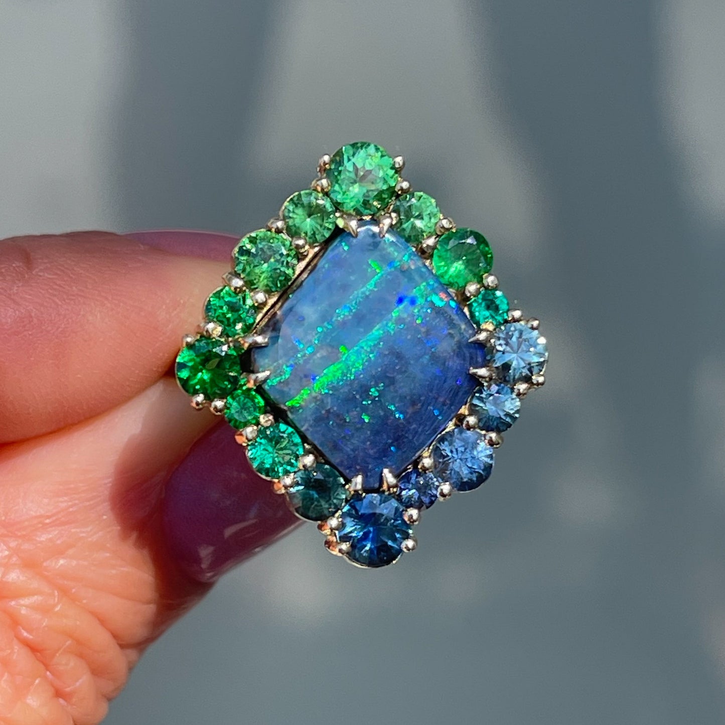 An Australian Opal Ring by NIXIN Jewelry. A gold opal ring with sapphires, emeralds and green garnets