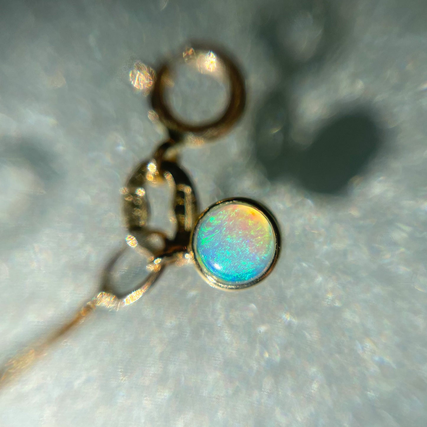 An Australian Opal Bracelet by NIXIN Jewelry shown under magnification. The bezel setting holds a blue green opal that hangs from the opal bracelet.