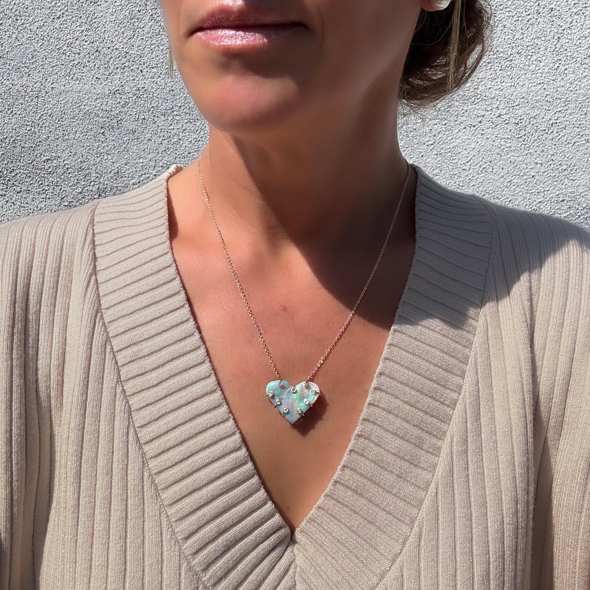 An Australian Opal Necklace by NIXIN Jewelry modeled on a woman, showing the scale and wearability of the luxury jewelry. The opal necklace is a striking statement piece of artisan jewelry that rests gracefully at the collarbone. This women's luxury necklace provides a high-end, elegant look.