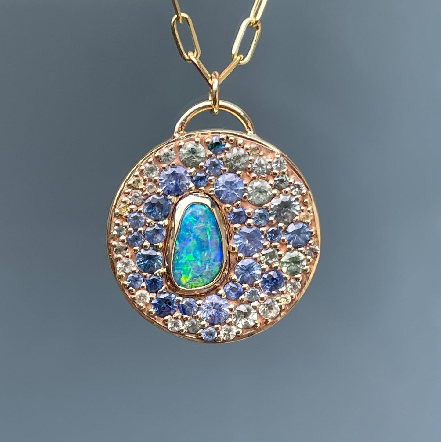 An Australian Opal Necklace by NIXIN Jewelry crafted with a bezel-set boulder opal and an array of sapphires in varying hues. This rare jewelry piece is a striking representation of opal and sapphire combinations in a fine art design.