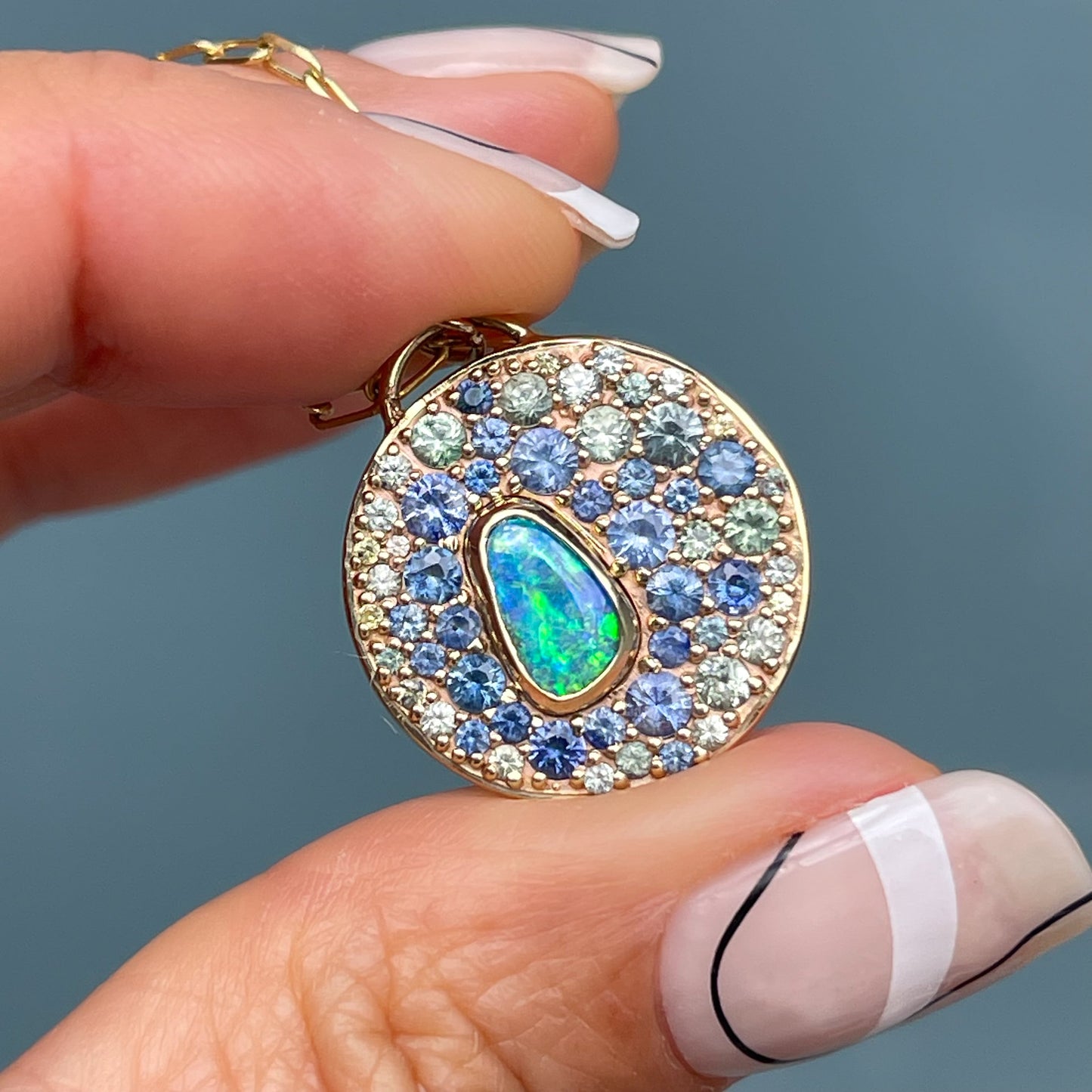 An Australian Opal Necklace by NIXIN Jewelry designed with a natural opal surrounded by fine sapphires. This women's luxury necklace exemplifies unique fine jewelry crafted with attention to detail and artistic composition.