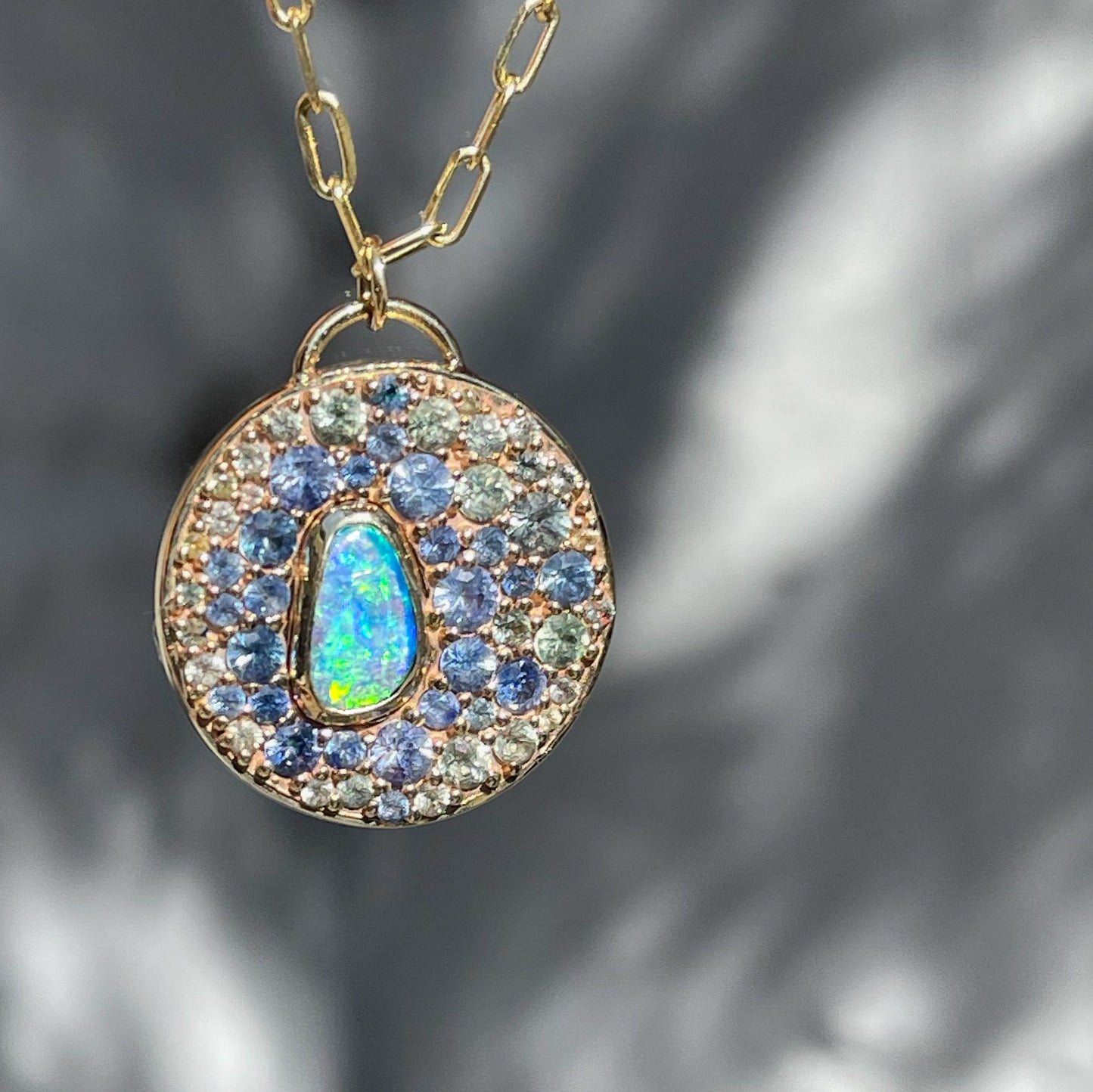 An Australian Opal Necklace by NIXIN Jewelry showcasing a boulder opal in a unique bezel setting, accented by teal sapphire and green sapphire. This rare opal necklace exemplifies luxury jewelry with bold, natural elements.
