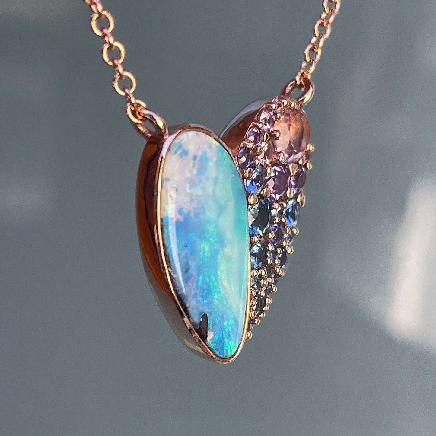 Side view of a Heart Opal Necklace by NIXIN Jewelry in rose gold with an Australian Opal and sapphires.