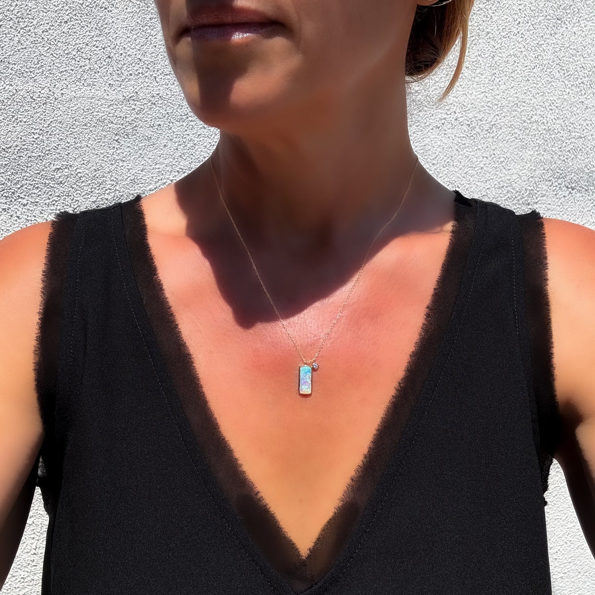 A model wearing an Australian Opal Necklace by NIXIN Jewelry to show scale. The piece of luxury jewelry features a Coober Pedy opal set in a bezel. This opal necklace is an example of unique opal jewelry, offering chic and sophisticated style.