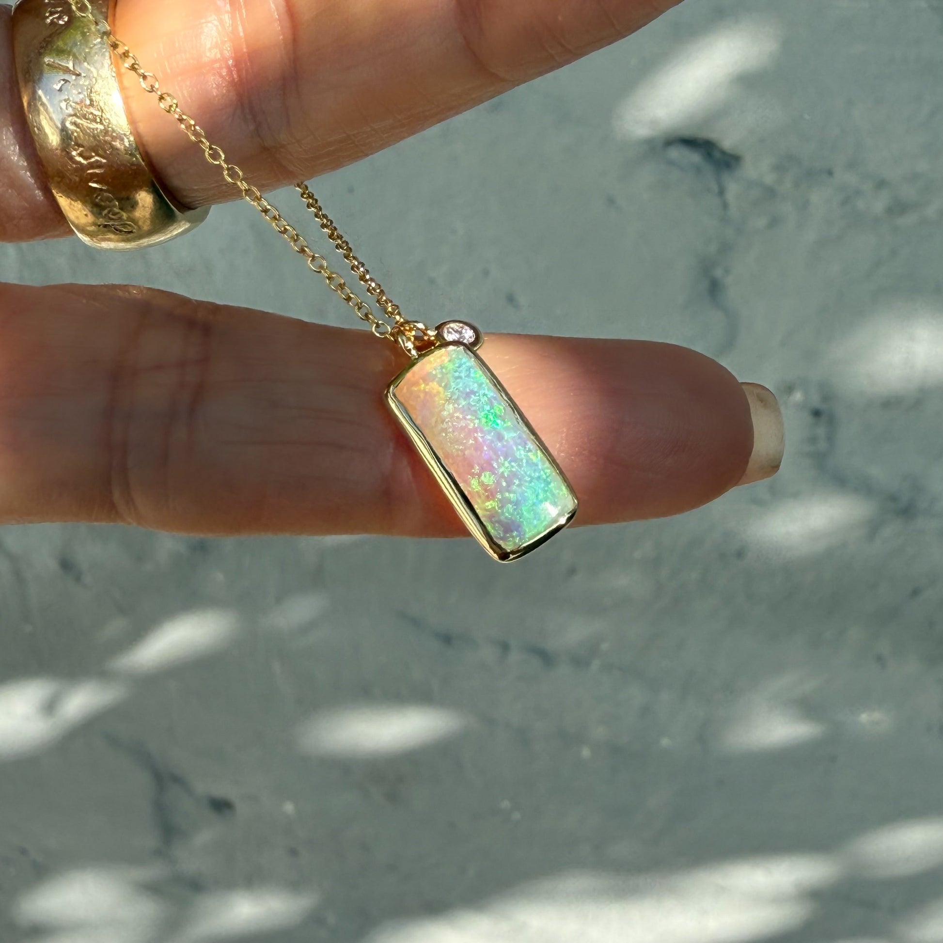 An Australian Opal Necklace by NIXIN Jewelry. This gold opal necklace features a breathtaking crystal opal set alongside a sparkling diamond. An example of elegant opal necklaces, combining natural beauty with a luxurious design.