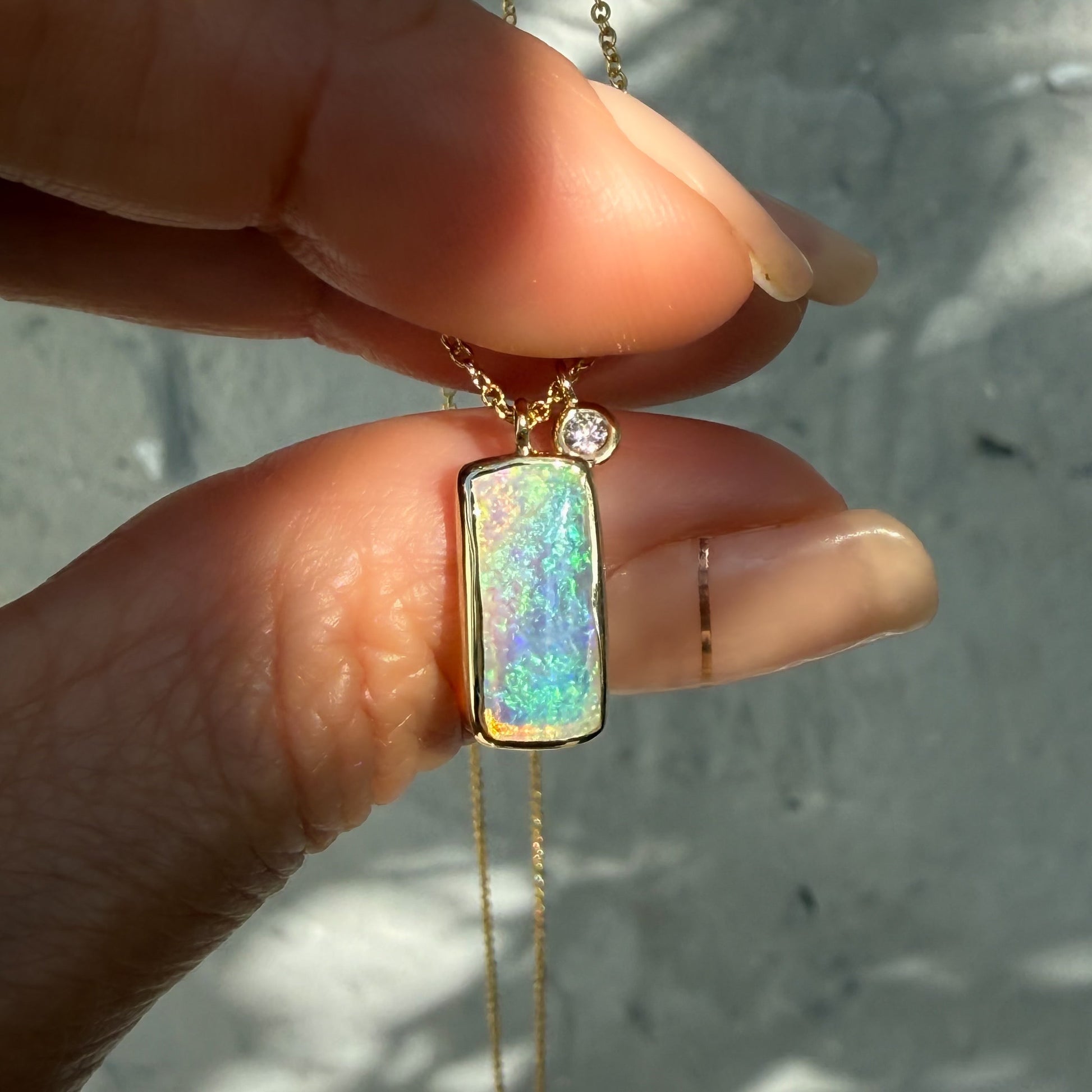 An Australian Opal Necklace by NIXIN Jewelry. The design showcases a natural opal stone in a bezel setting, creating a sophisticated opal pendant. A beautiful representation of australian opal jewelry and makes for a beautifully luxurious gift.
