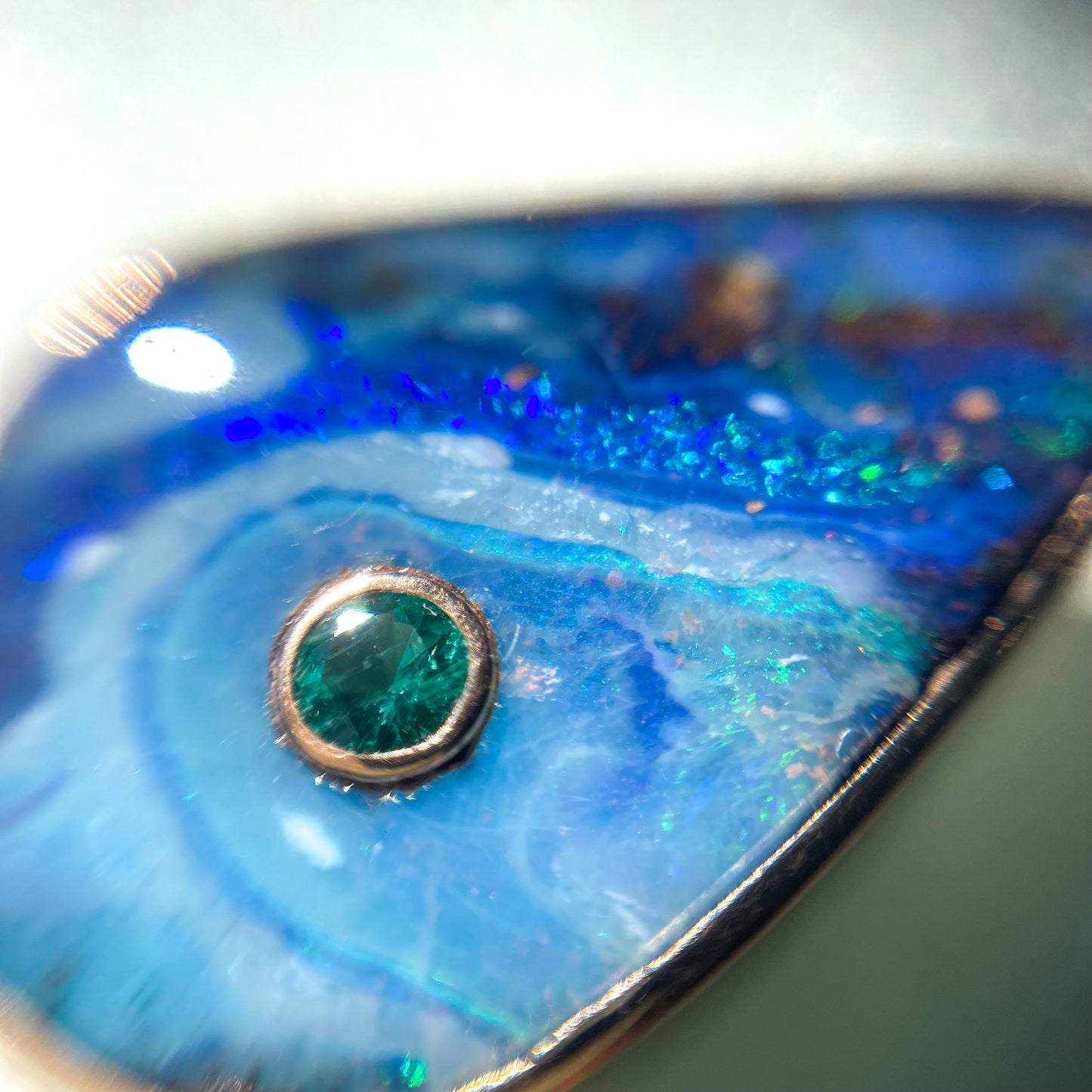 Magnified shot of an Australian Opal Necklace by NIXIN Jewelry. Image shows the emerald and Boulder Opal in bezel setting.