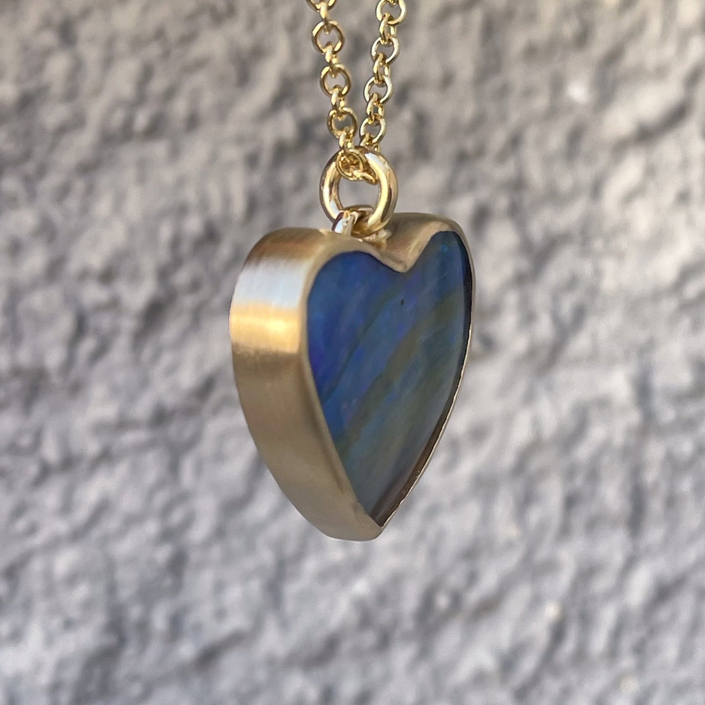 Profile view of an Australian Opal Necklace by NIXIN Jewelry showing the matte gold of the bezel setting.
