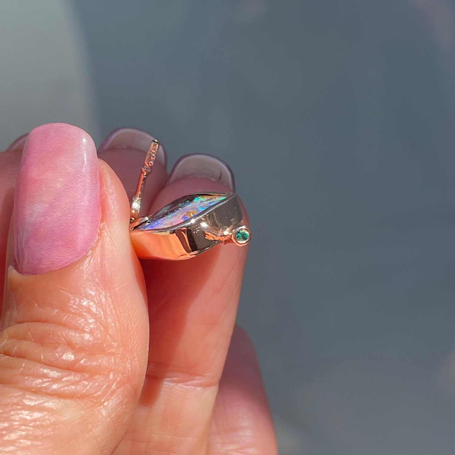 Angled shot of an Australian Opal Necklace by NIXIN Jewelry showing an emerald set in the rose gold mushroom stem.