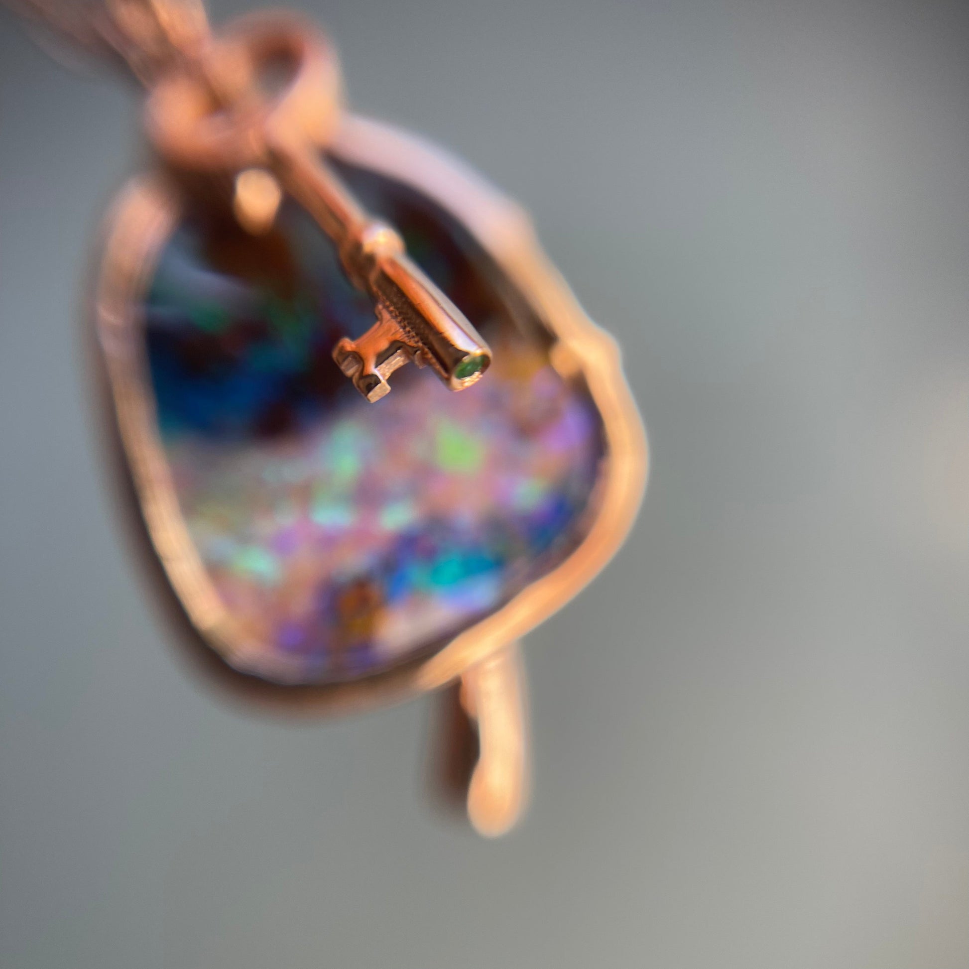Close up of the emerald set into a rose gold key charm on Australian Opal Necklace by NIXIN Jewelry.