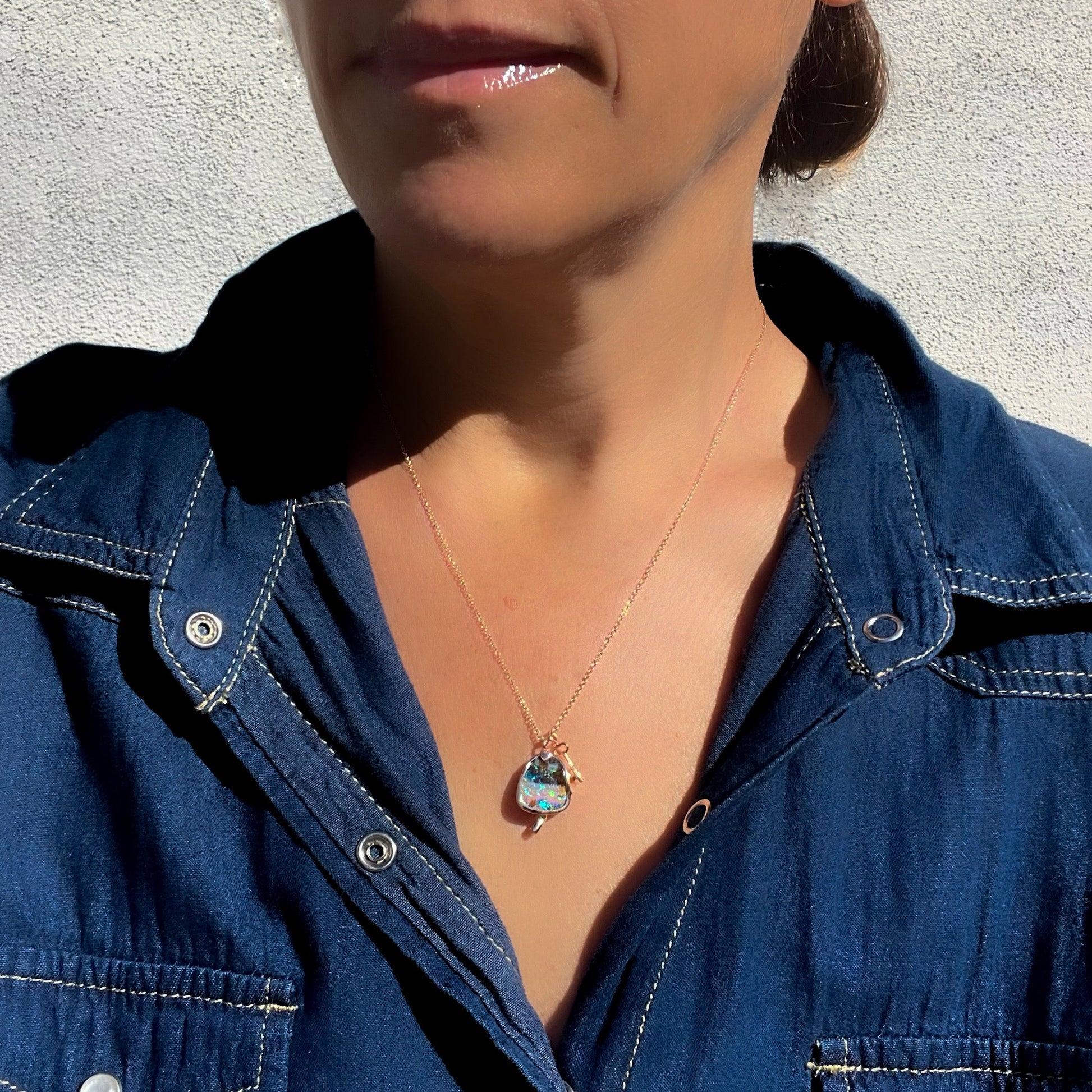 Model wearing an Australian Opal Necklace by NIXIN Jewelry. A mushroom opal necklace with a tiny key charm.