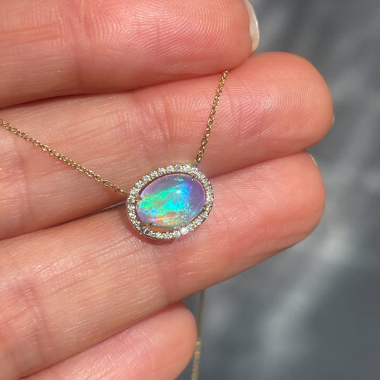 An Australian Opal Necklace by NIXIN Jewelry is crafted from 14K yellow gold with a luminous crystal opal. This opal and diamond necklace is a luxurious, unique fine jewelry statement designed for timeless elegance.