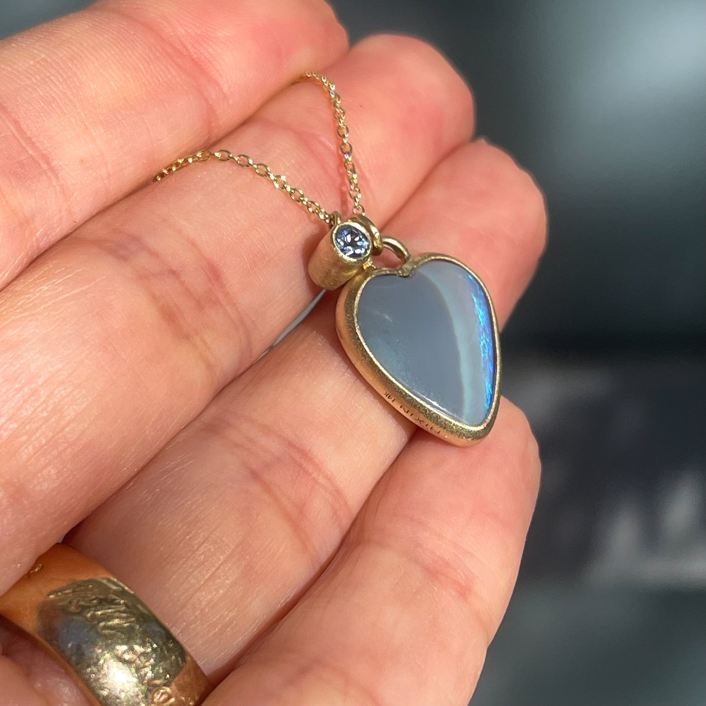 Side view of an Australian Opal Necklace and sapphire charm showing the bezel edges.