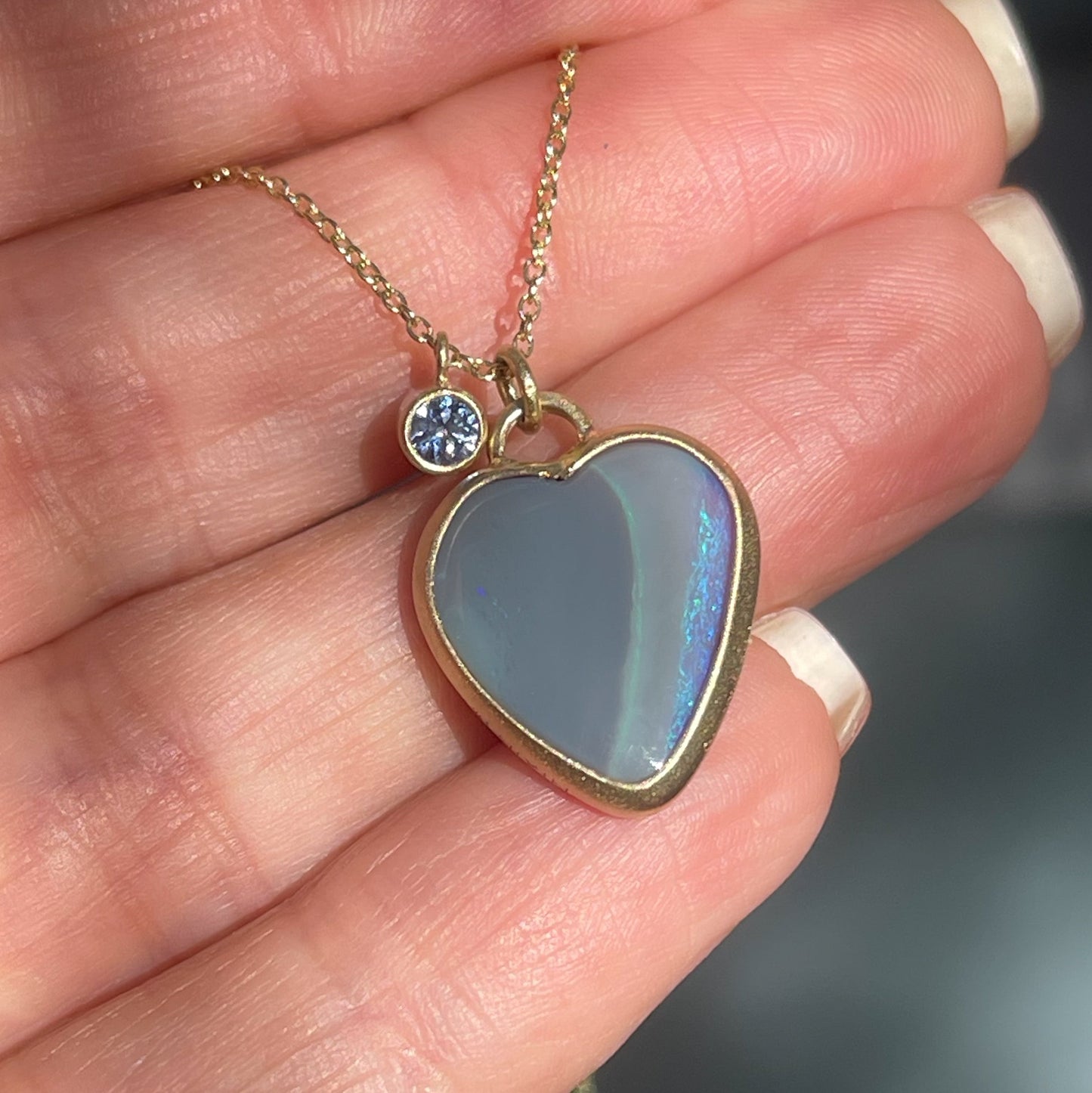 An Australian Opal Necklace by NIXIN Jewelry with a semi black opal in a matte gold bezel setting.