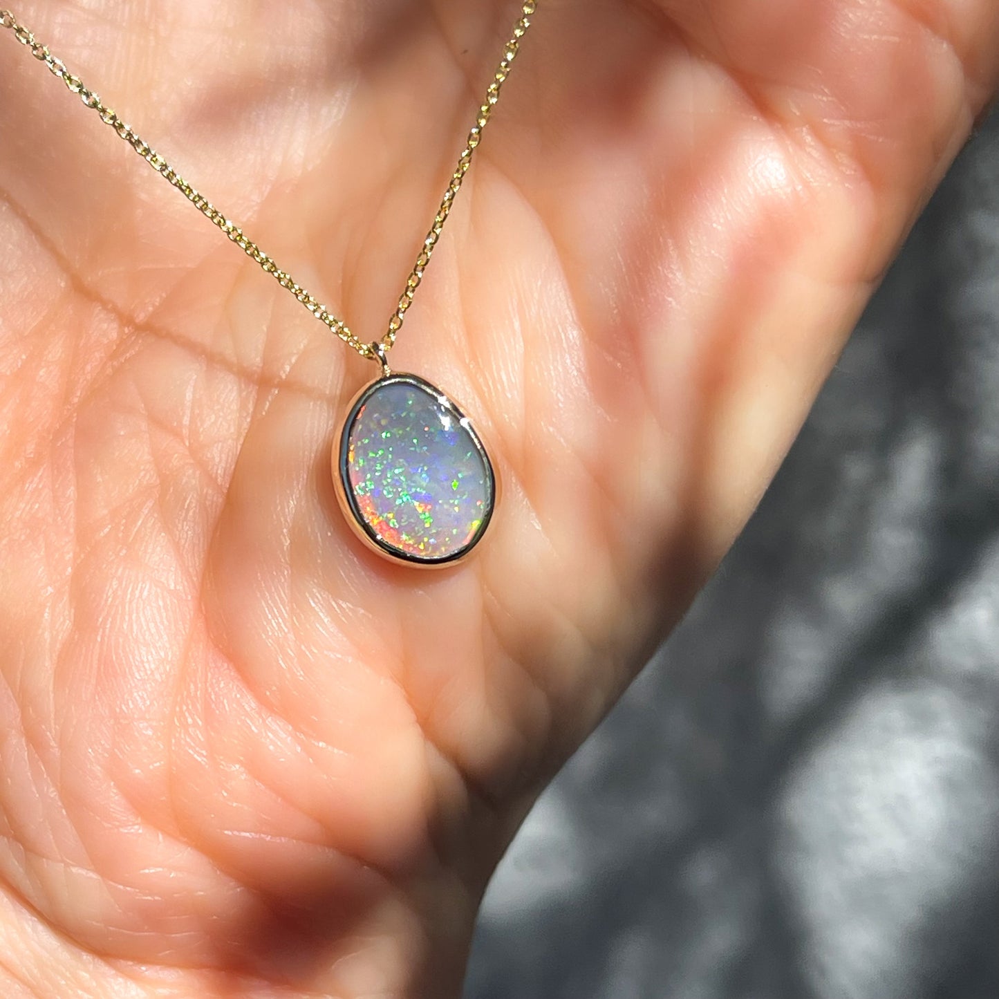 An Australian Opal Necklace by NIXIN Jewelry in a bezel setting on a dainty gold chain.