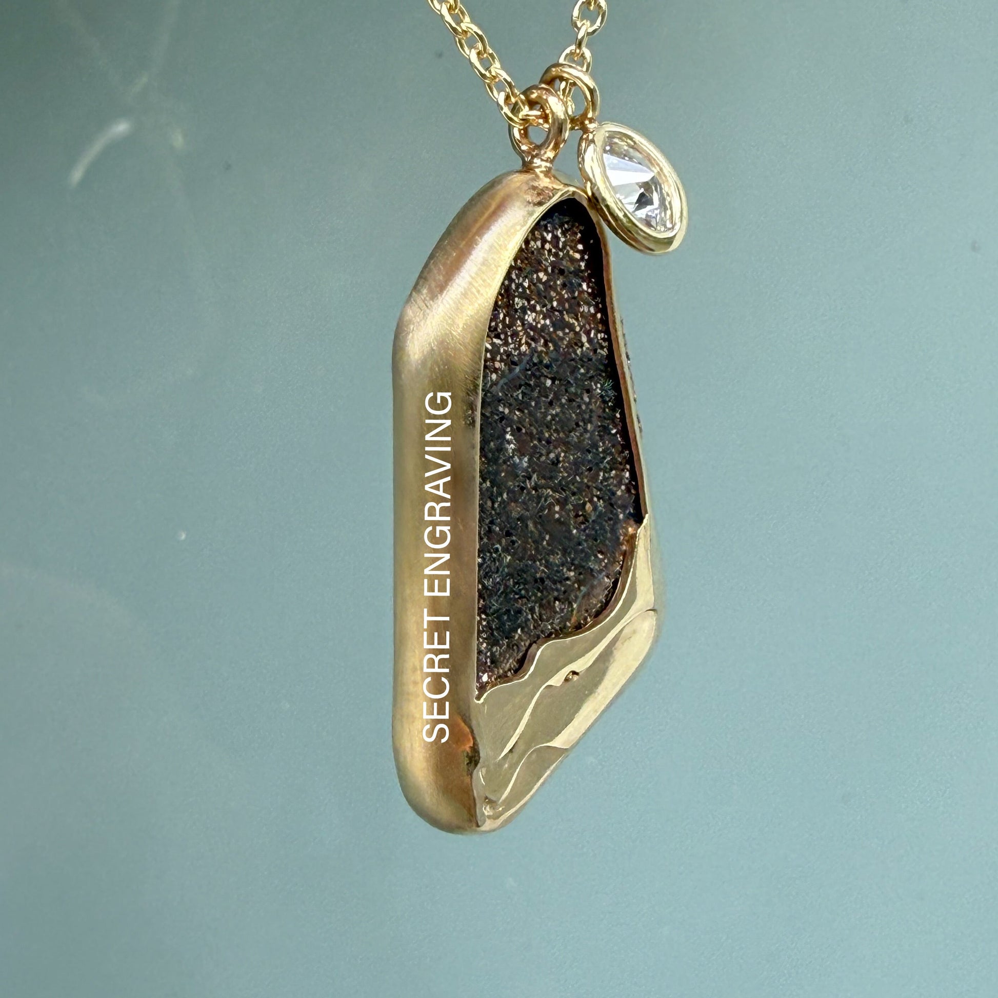 Detail shot of the side and back of an Australian Opal Necklace by NIXIN Jewelry. The opal pendant has exposed matrix on back and a secret engraving. The design of the gold opal necklace is unique and one of a kind.