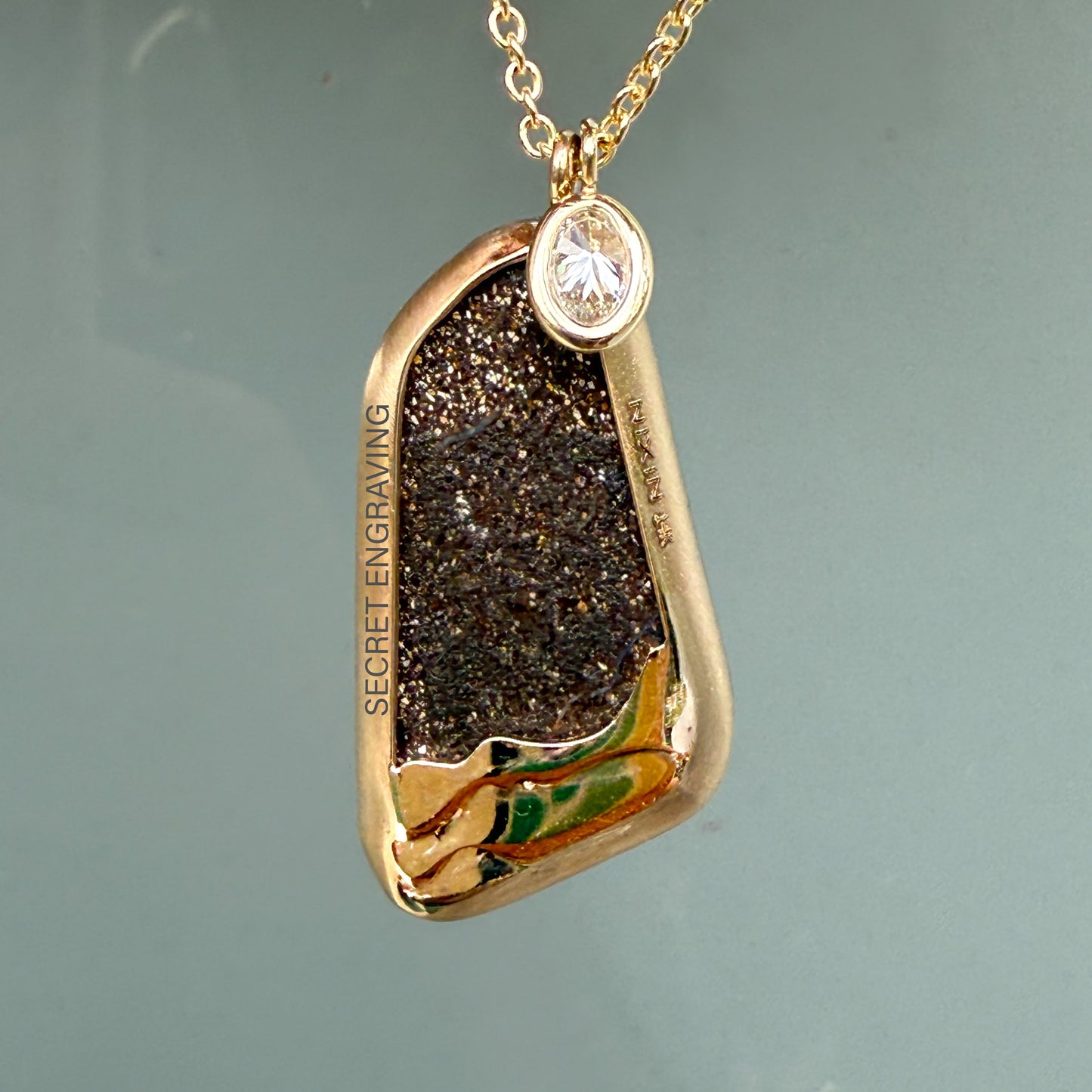 Rear view of an Australian Opal Necklace by NIXIN Jewelry showing the raw texture of the boulder opal's matrix and the polished gold art detail of oceanic waves. The visible ironstone matrix confirms the boulder opal necklace origin. This rare opal jewelry is highly collectible.