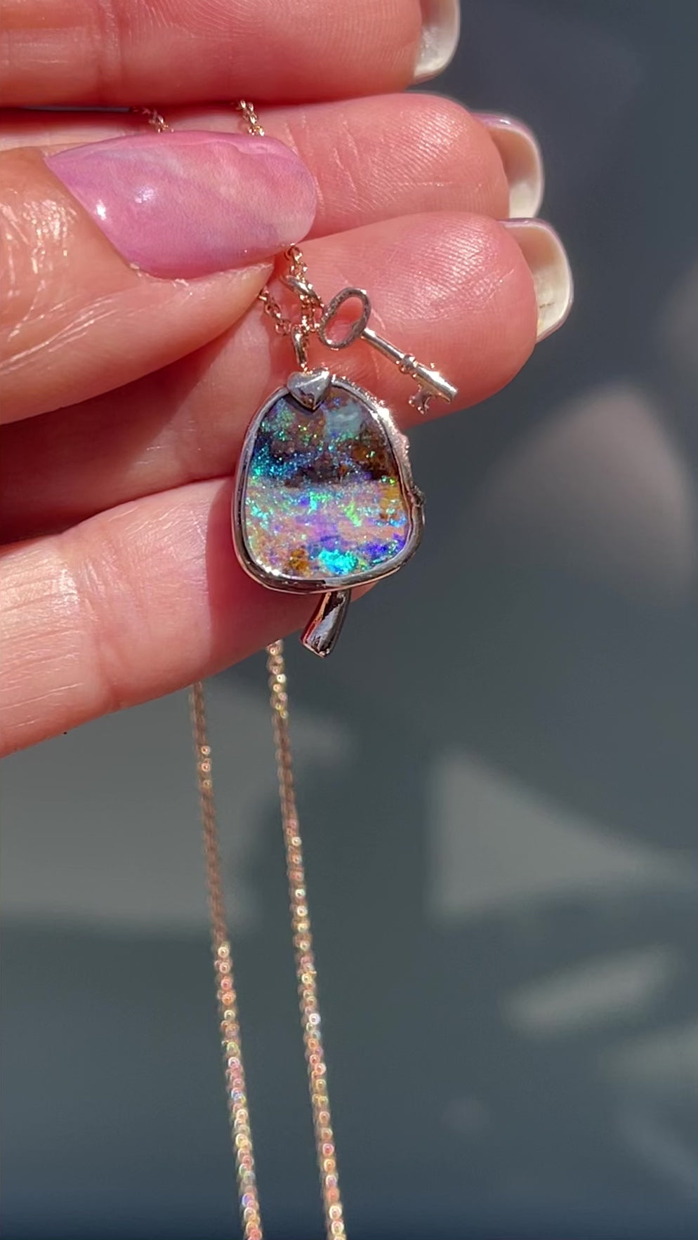 Video of an Australian Opal Necklace by NIXIN Jewelry with a sliding key charm and hidden emeralds.