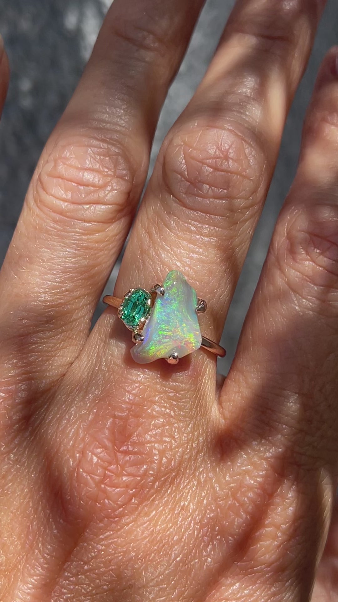 Video of an Opal and Emerald Ring by NIXIN Jewelry modeled on a hand. The Black Opal ring is made in rose gold with a vibrant green emerald.