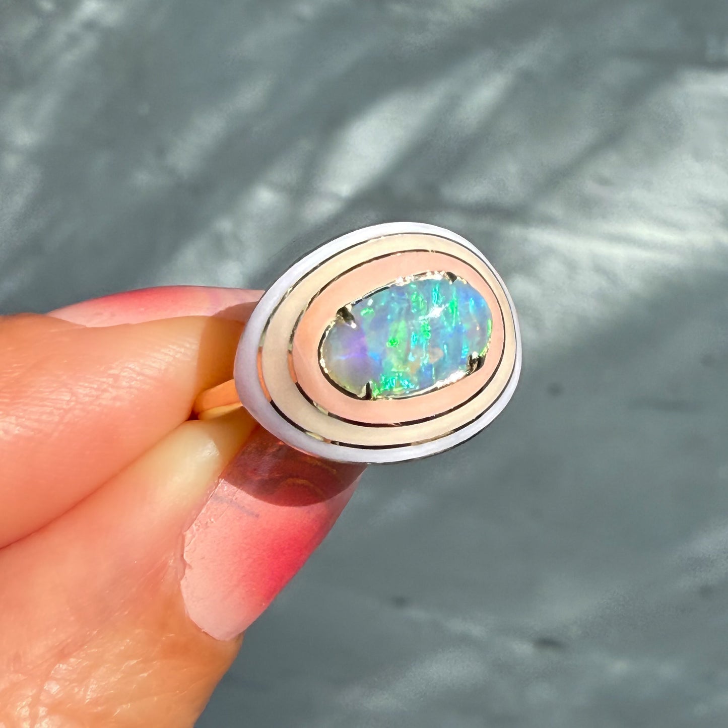 An Australian Opal Ring by NIXIN Jewelry, with a view of the oval crystal opal and its distinctive ombre enamel halo. This luxury opal ring is a perfect example of rare opal jewelry and is a top choice for ladies opal rings.