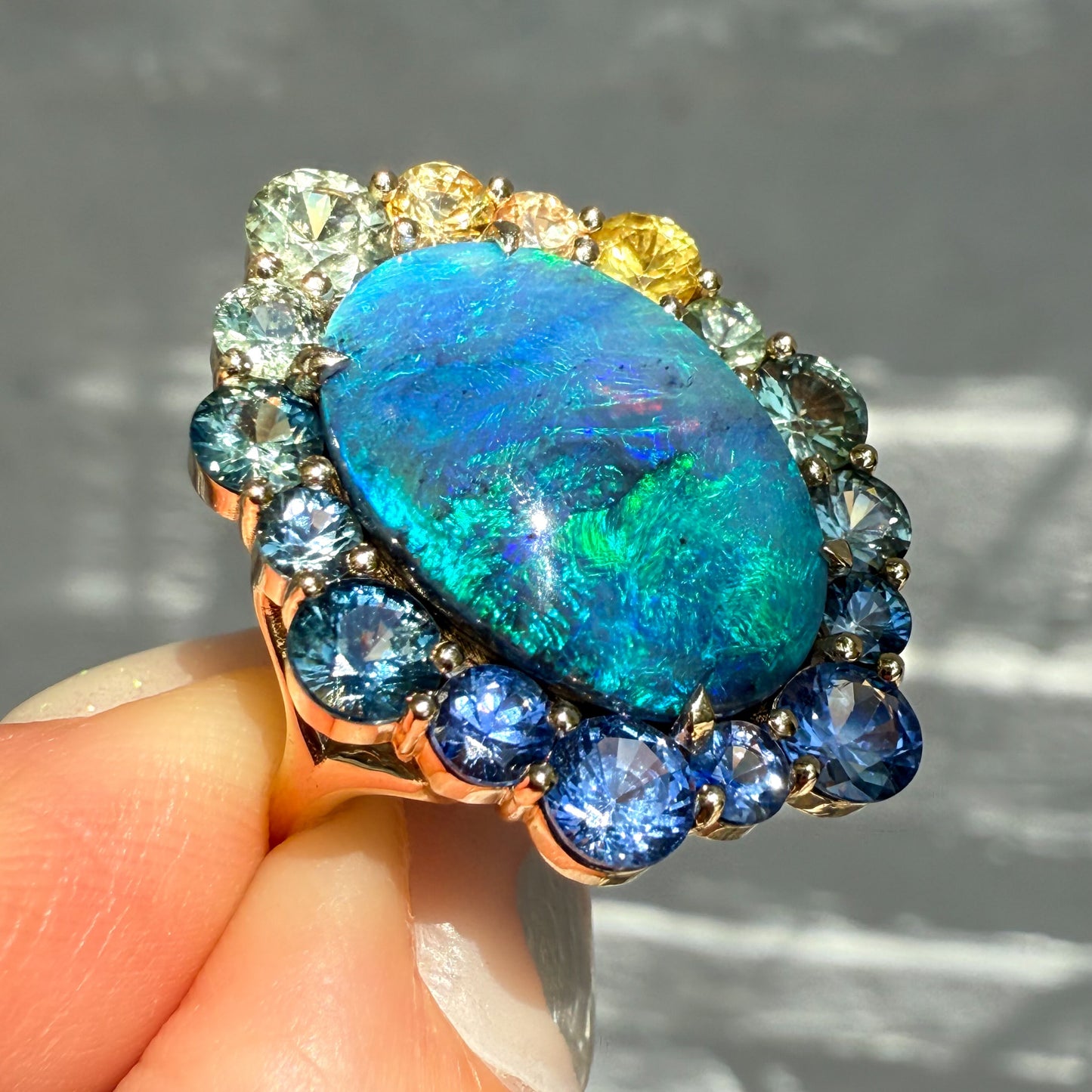 Side view of an Australian Opal Ring by NIXIN Jewelry. This sapphire opal ring is a stunning example of fine jewelry. It is an ideal women's luxury ring for a collector of rare Australian opal.