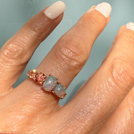An Australian Opal Ring by NIXIN Jewelry worn on a hand, clearly showing the scale and design of this unique fine jewelry cocktail ring. The rose gold opal ring showcases two opals and sapphire ring accents, emphasizing the warm tones. This is a must-have modern opal ring for luxury collectors.