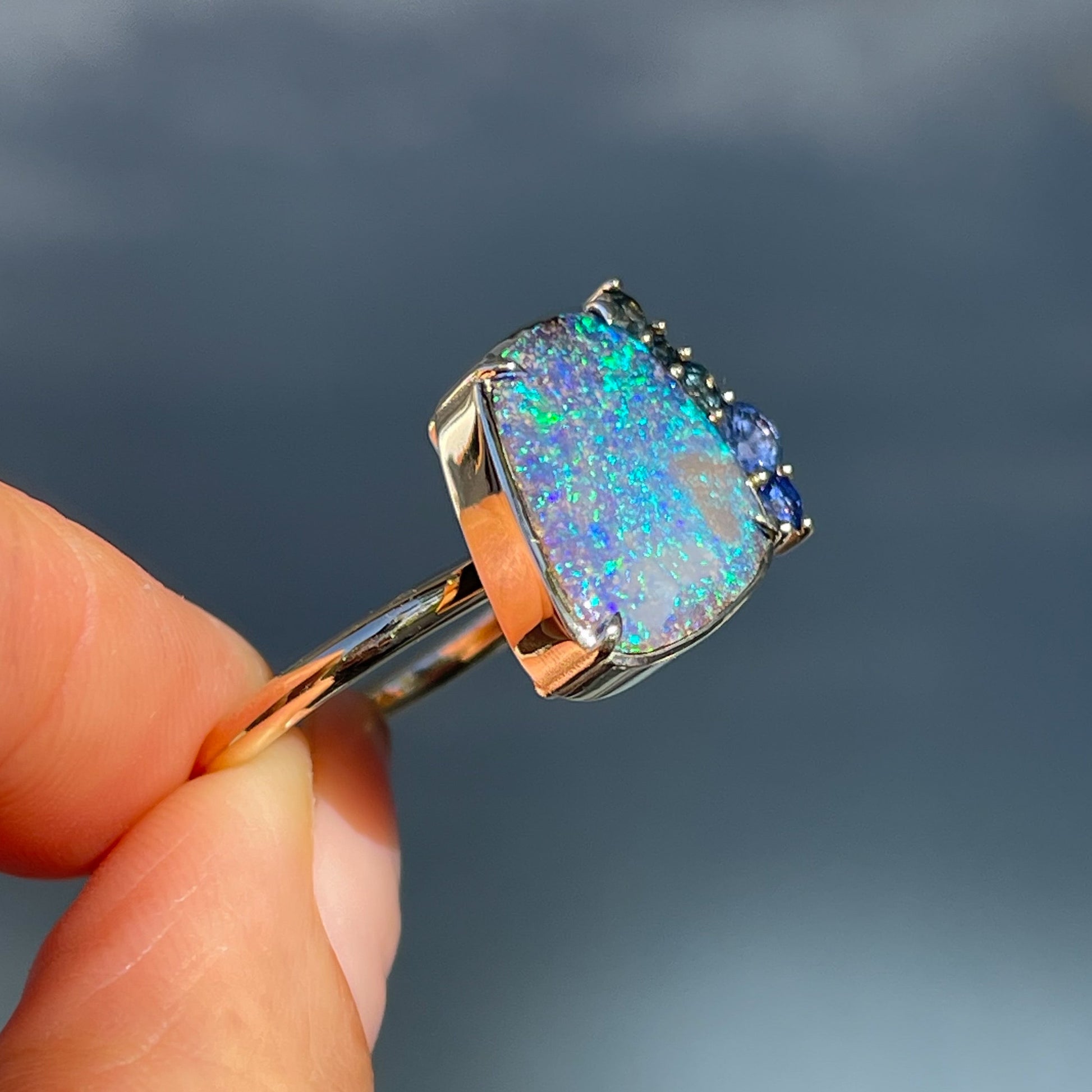 A side view of an Australian Opal Ring by NIXIN Jewelry. A blue opal ring made in yellow gold.