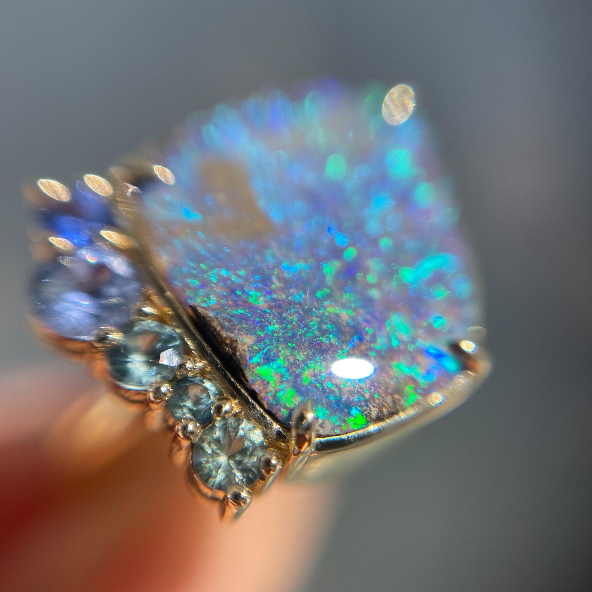 Magnified shot of an Australian Opal Ring by NIXIN Jewelry. Shows the boulder opal and green sapphires in the unique opal ring.