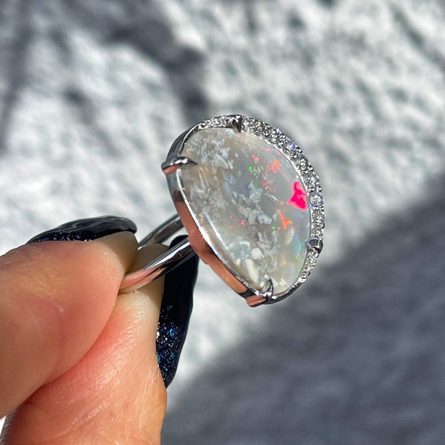 Side view of an Australian Opal Ring by NIXIN Jewelry showing the prong setting of the Black Opal and opposing diamond halo.