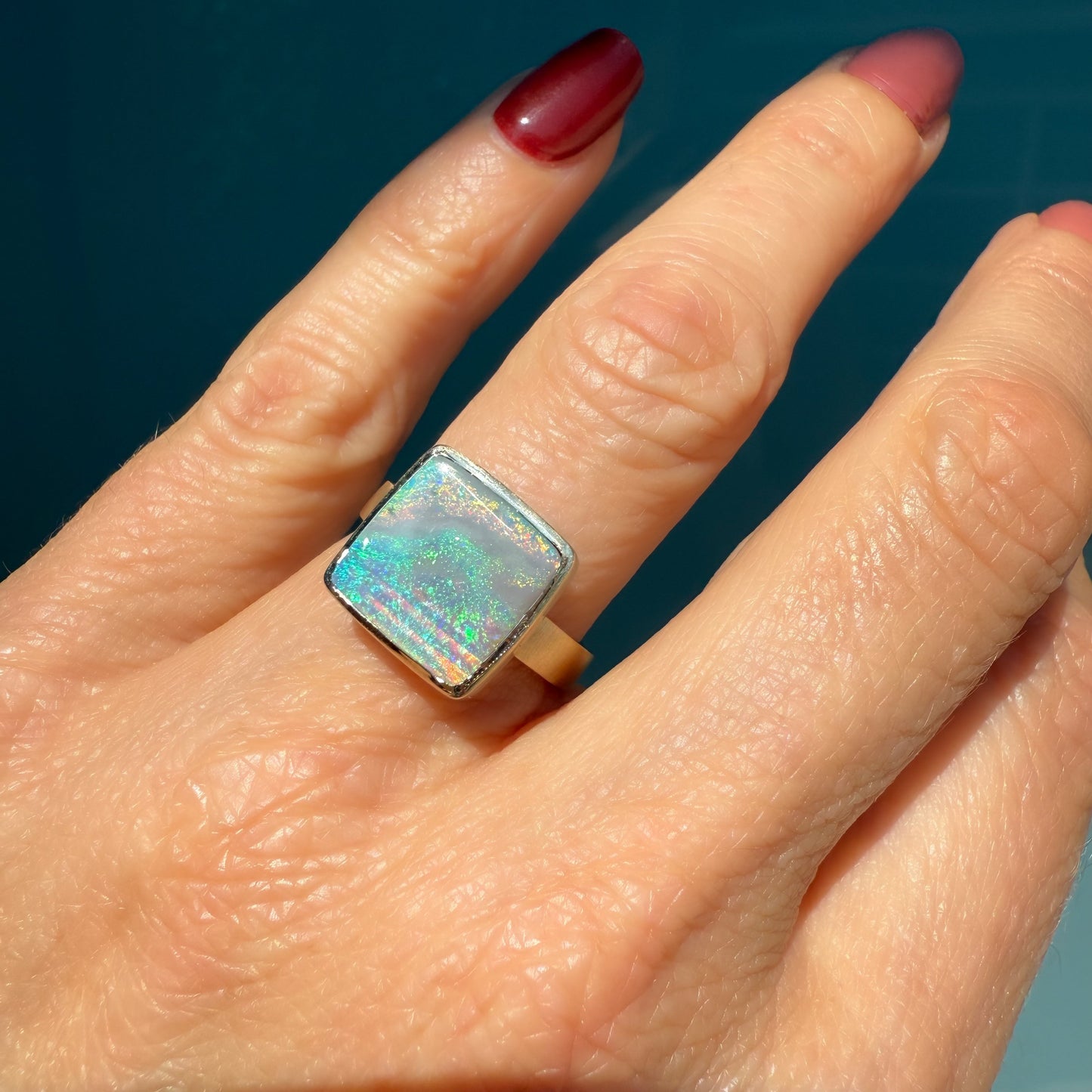 An Australian Opal Ring by NIXIN Jewelry, set in a sleek bezel. This modern opal ring is an example of exquisite jewelry art, designed for luxury.
