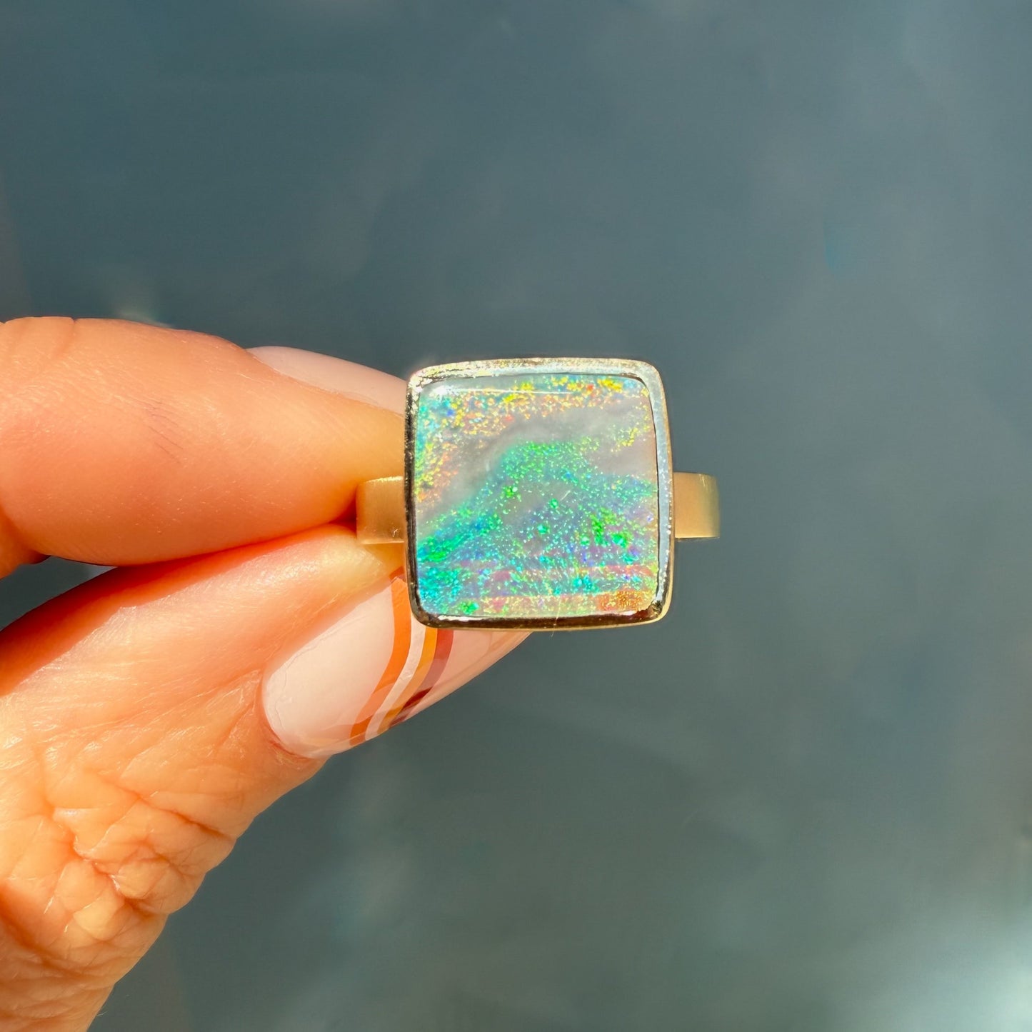 An Australian Opal Ring by NIXIN Jewelry, with a prominent black opal. This rare opal ring highlights unique fine jewelry craftsmanship in a gold opal ring.