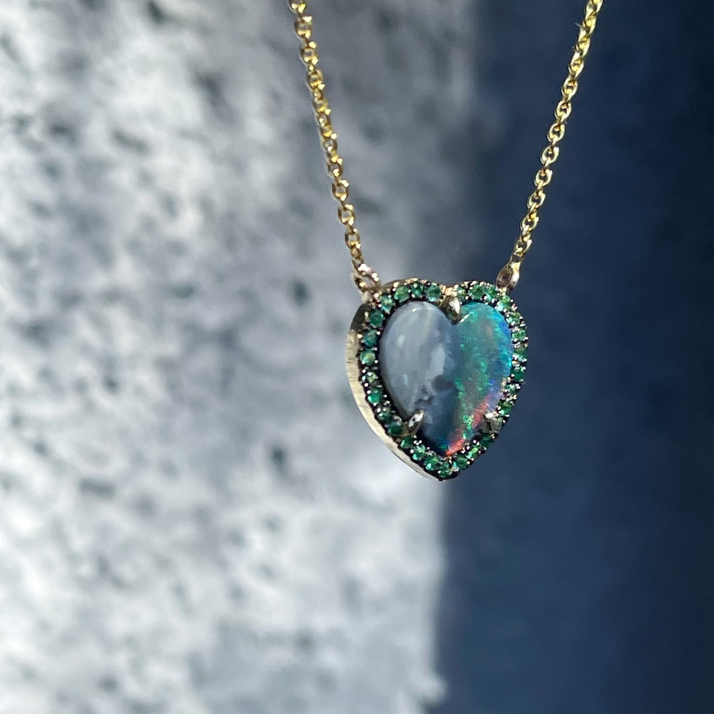 Side shot of an Australian Opal Heart Necklace by NIXIN Jewelry. The Australian Opal Necklace has a Black Opal set in gold..