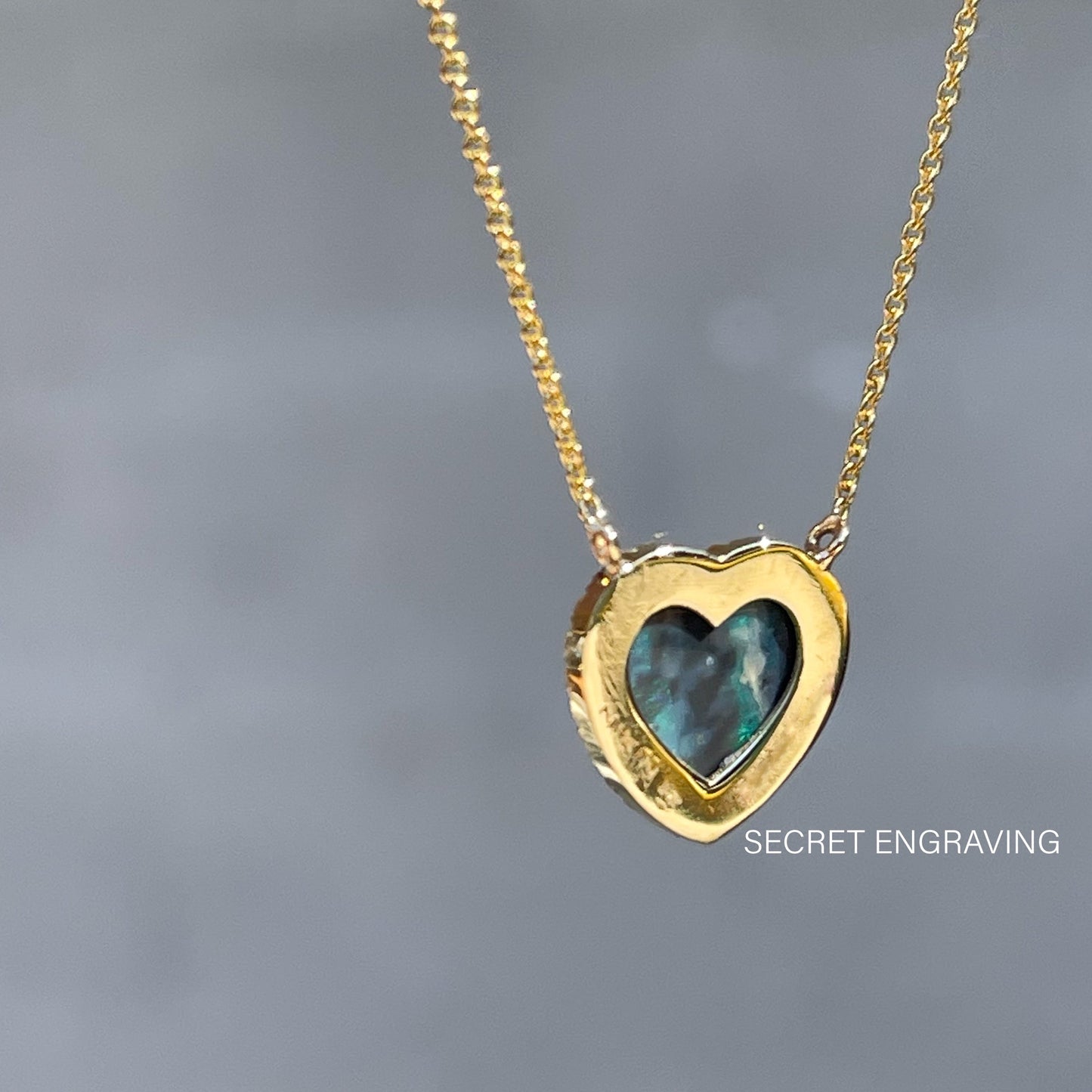 A view of the back of an Australian Opal Heart Necklace by NIXIN Jewelry. It shows the heart shape of the Black Opal.