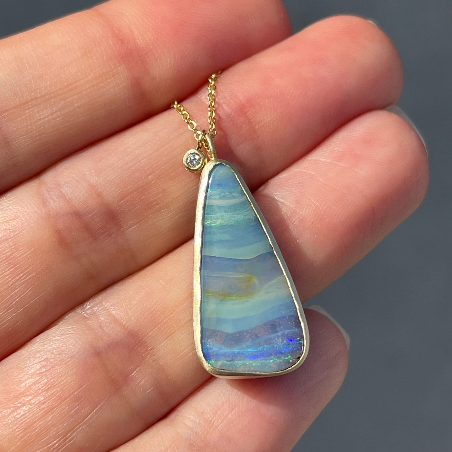Australian opal necklace by NIXIN Jewelry held in sunlight