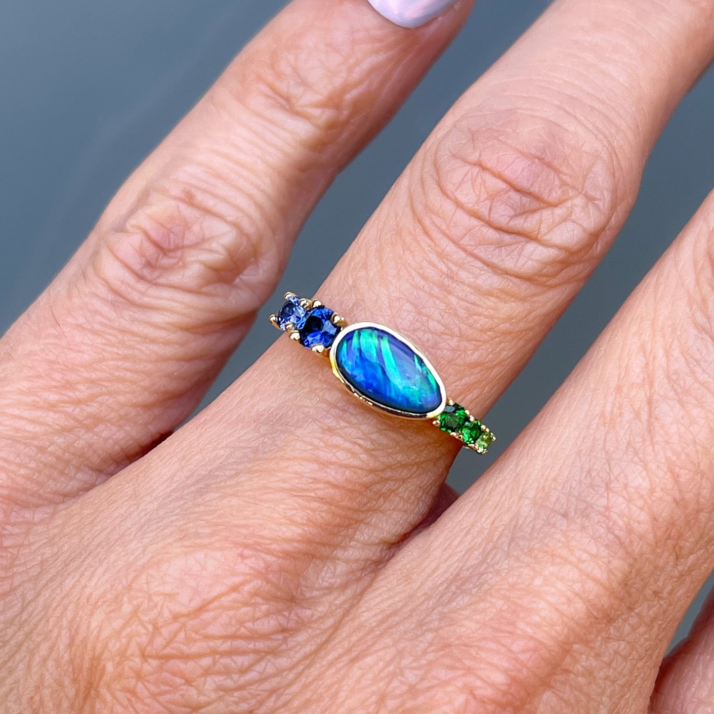 Black Opal Ring by NIXIN Jewelry modeled on hand. Blue opal ring in 14k gold.