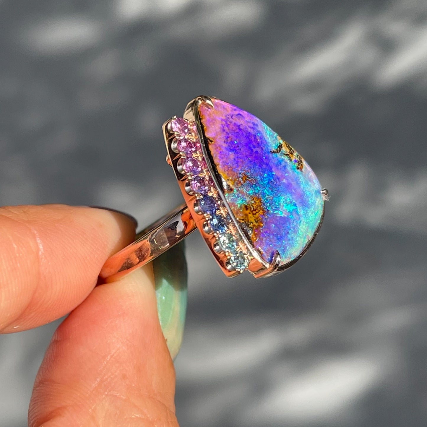An Australian Opal Ring by NIXIN Jewelry featuring a purple opal is shown from the side.