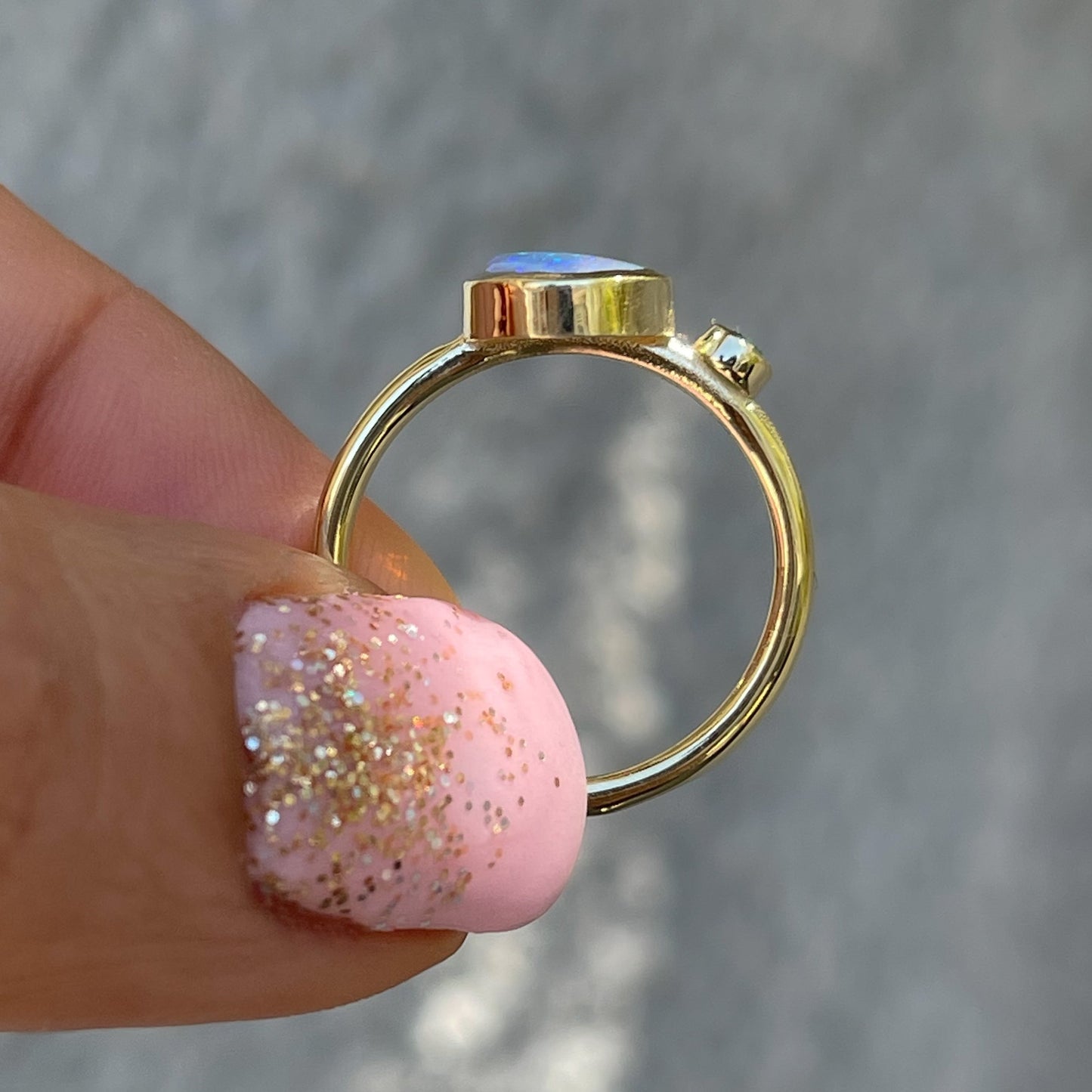 An Australian Opal Ring shown in profile. Made in 14k gold with an emerald and opal.