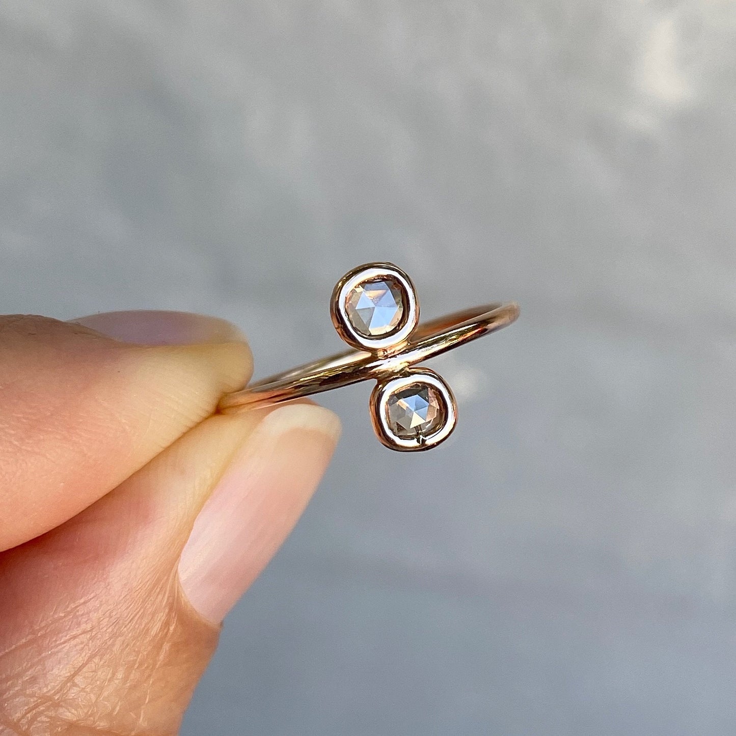 Paleo Double Diamond Slice Rose Gold Ring held between fingers