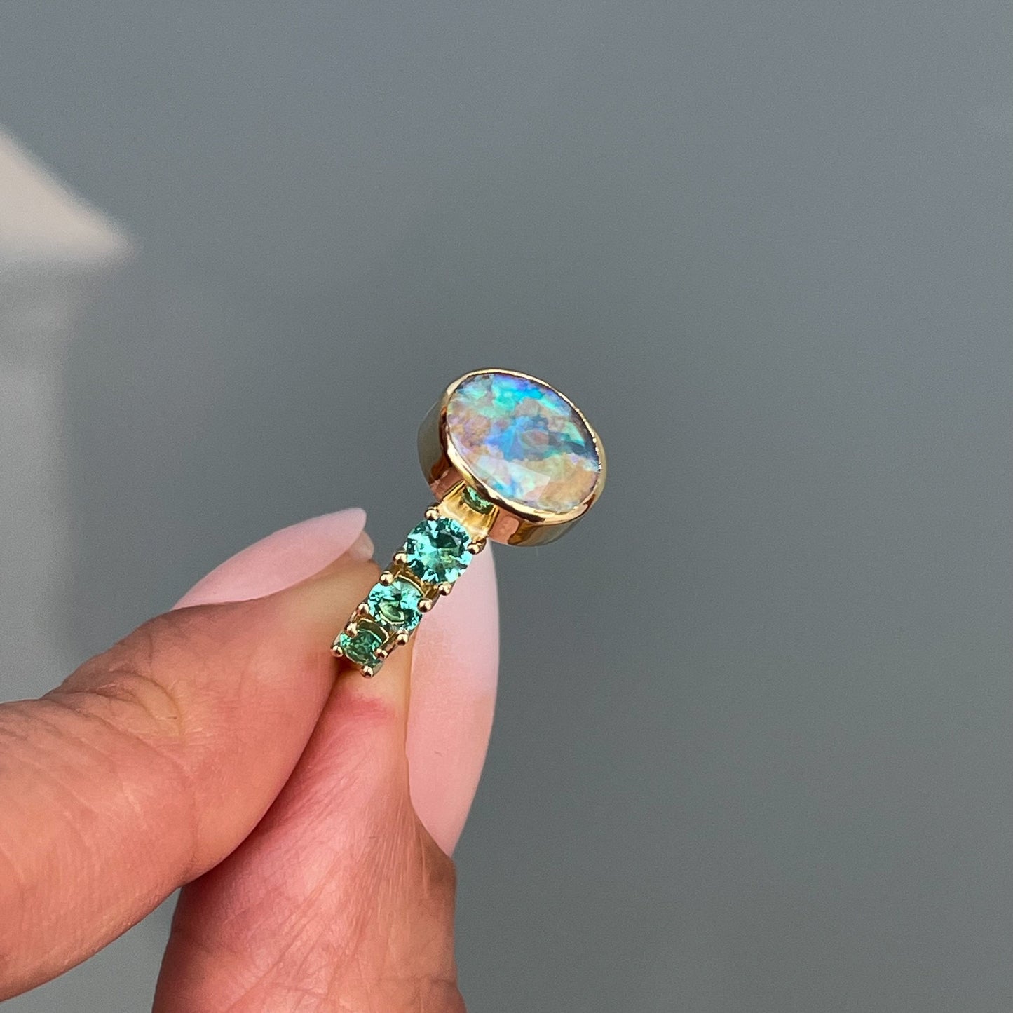 Opal and Zambian Emerald ring by NIXIN Jewelry held in profile