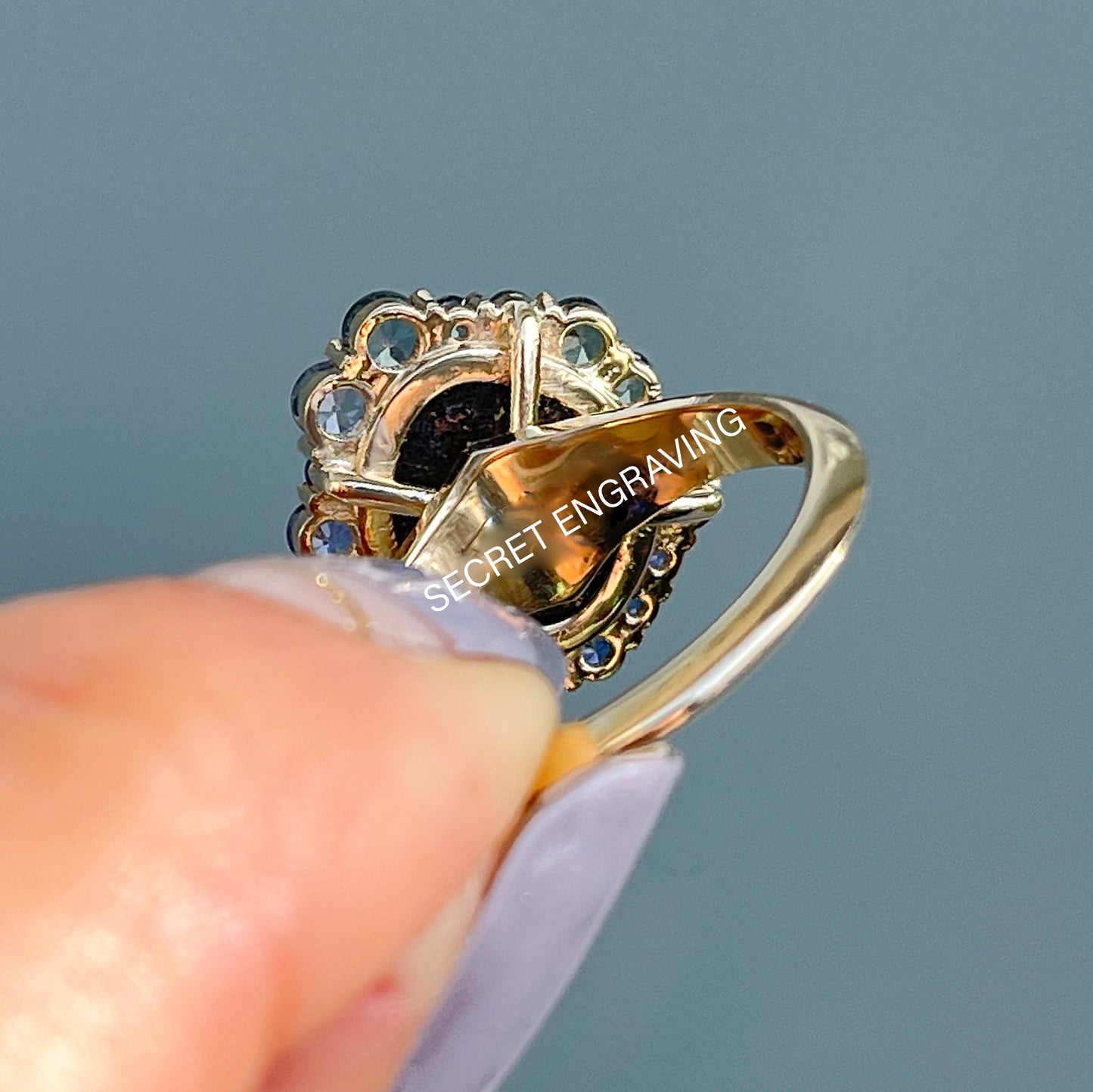 Australian Opal Ring by NIXIN Jewelry held in front of glass door. Image shows back of setting and location of secret engraving.