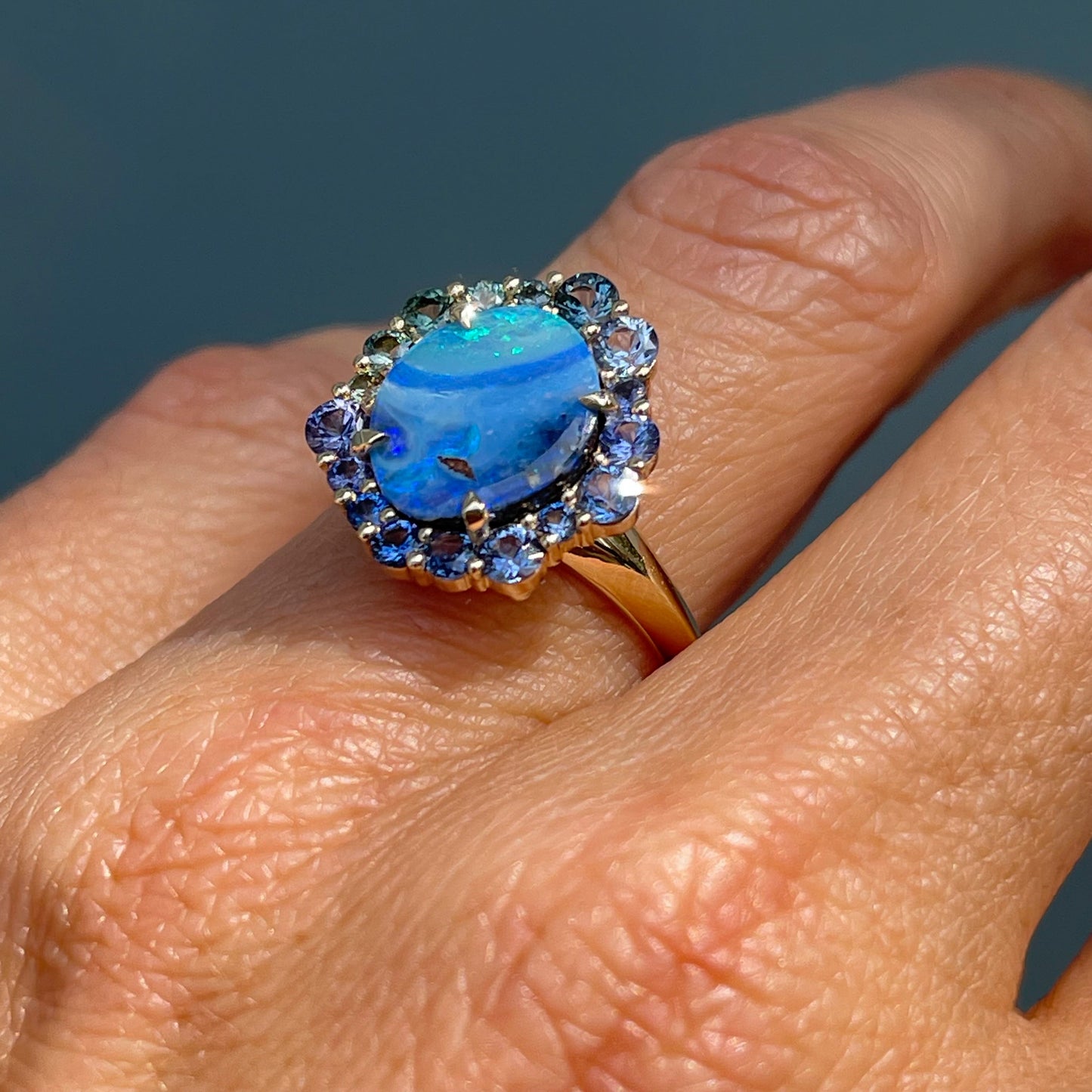 Australian Opal Ring by NIXIN Jewelry modeled on hand in sun. Shows the knife edge band under the natural opal ring.