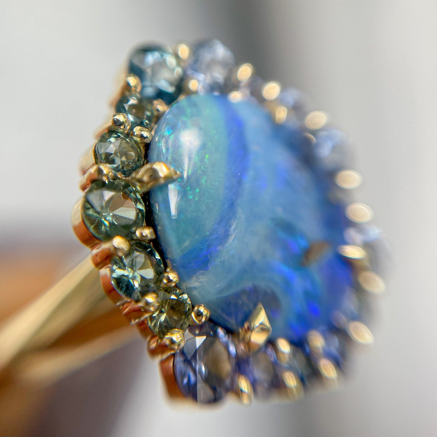 Australian Opal Ring by NIXIN Jewelry with ombre sapphire halo shot under magnification.