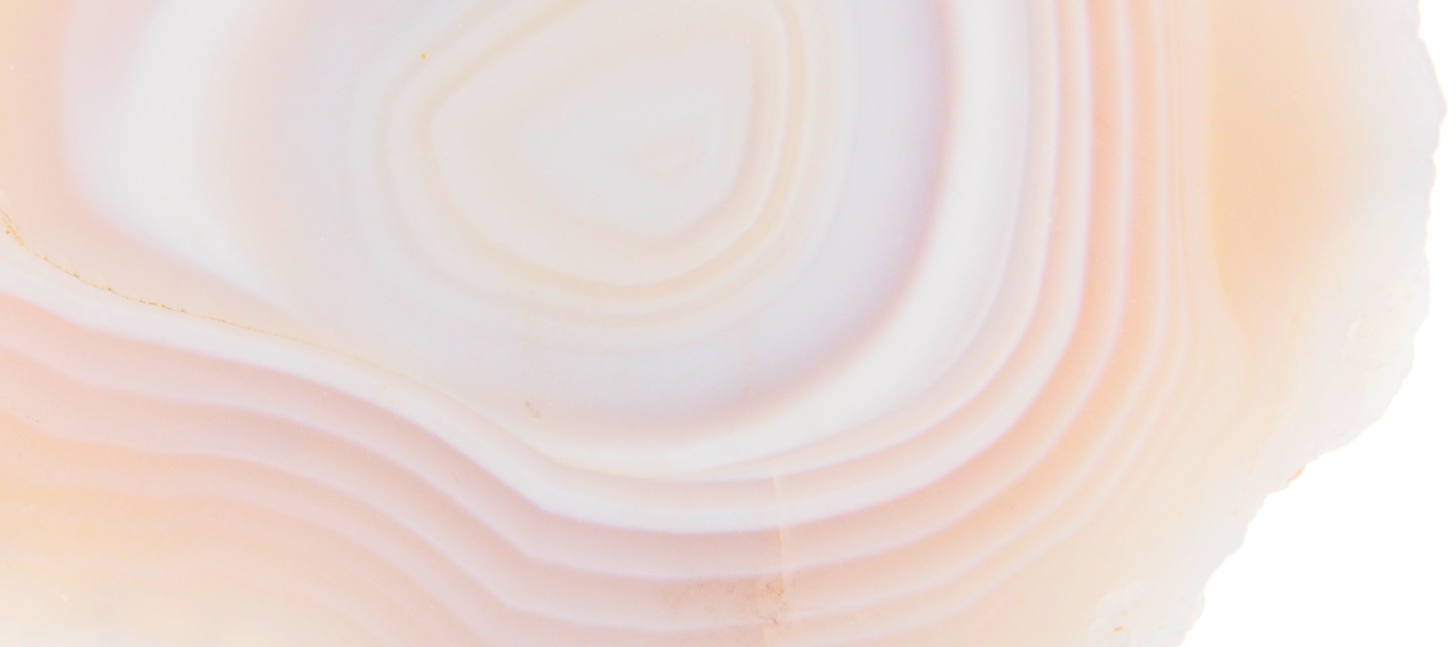 Image of a peach agate slice showing its raw edge along one side of the image.