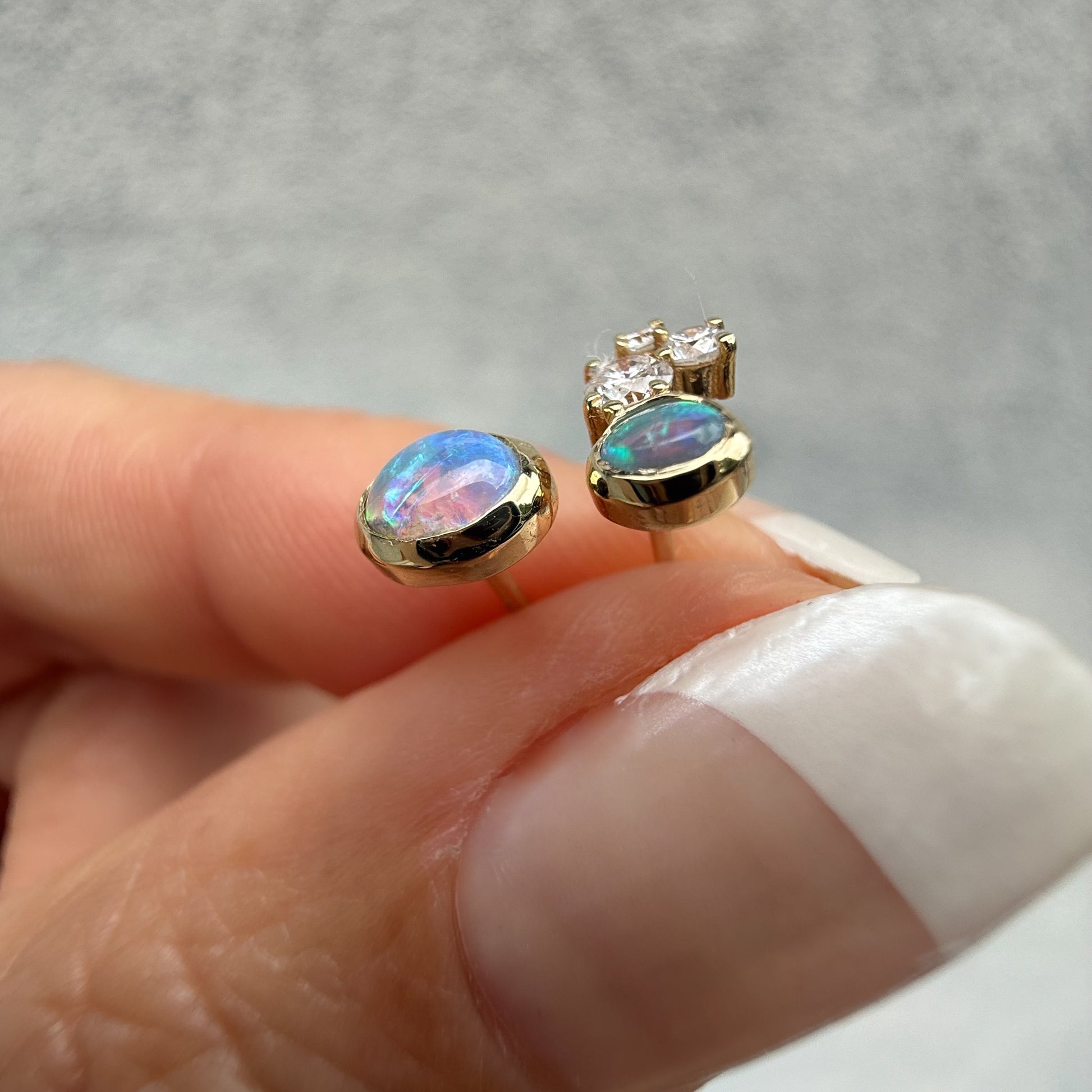 Australian Opal Earrings by NIXIN Jewelry. Profile view of the opal studs, highlighting the stunning play-of-color, including bright pink and blue, in the crystal opal and black opal. We offer rare opal jewelry and unique opal jewelry for sale.
