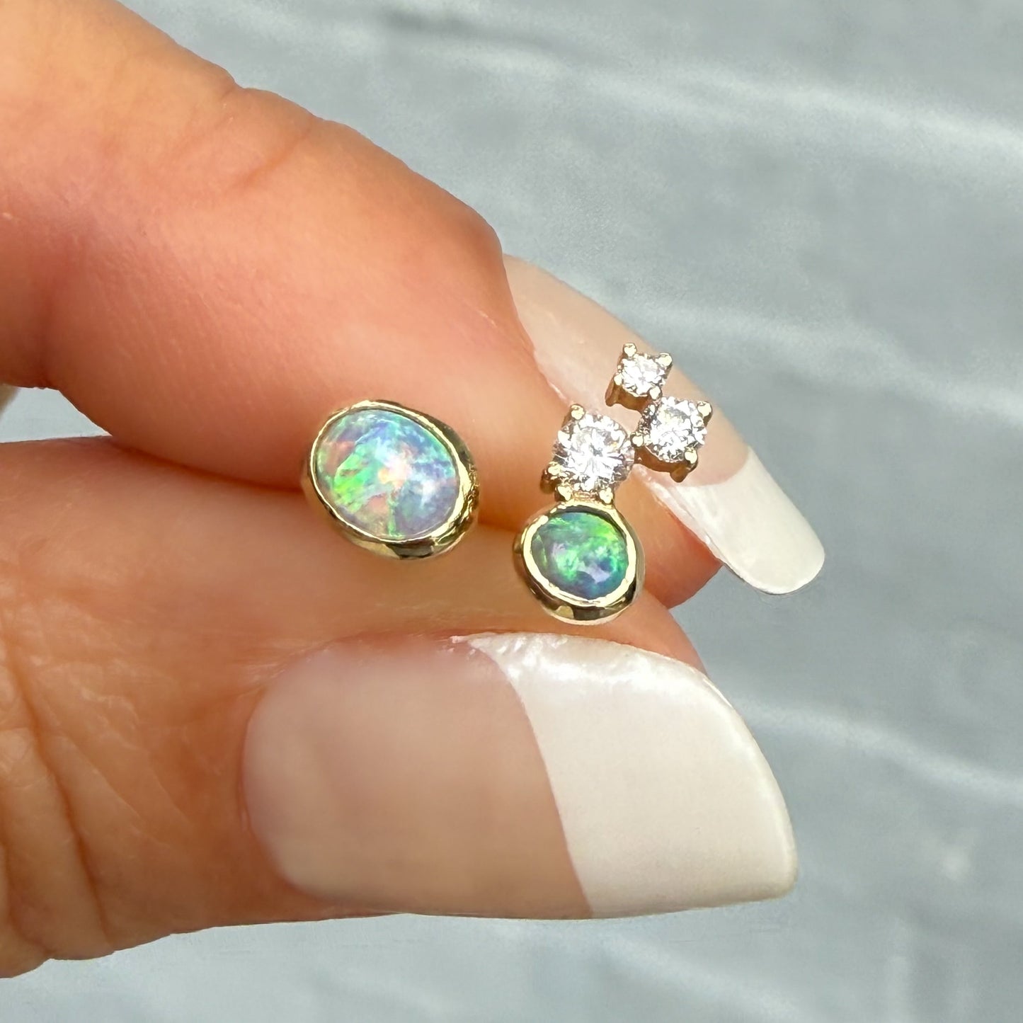 Australian Opal Earrings by NIXIN Jewelry. Mismatched opal stud earrings showcasing two unique black crystal opal stones. The larger opal stone flashes rare lavender, green, and peach hues, offering unique jewelry in a modern opal jewelry design.